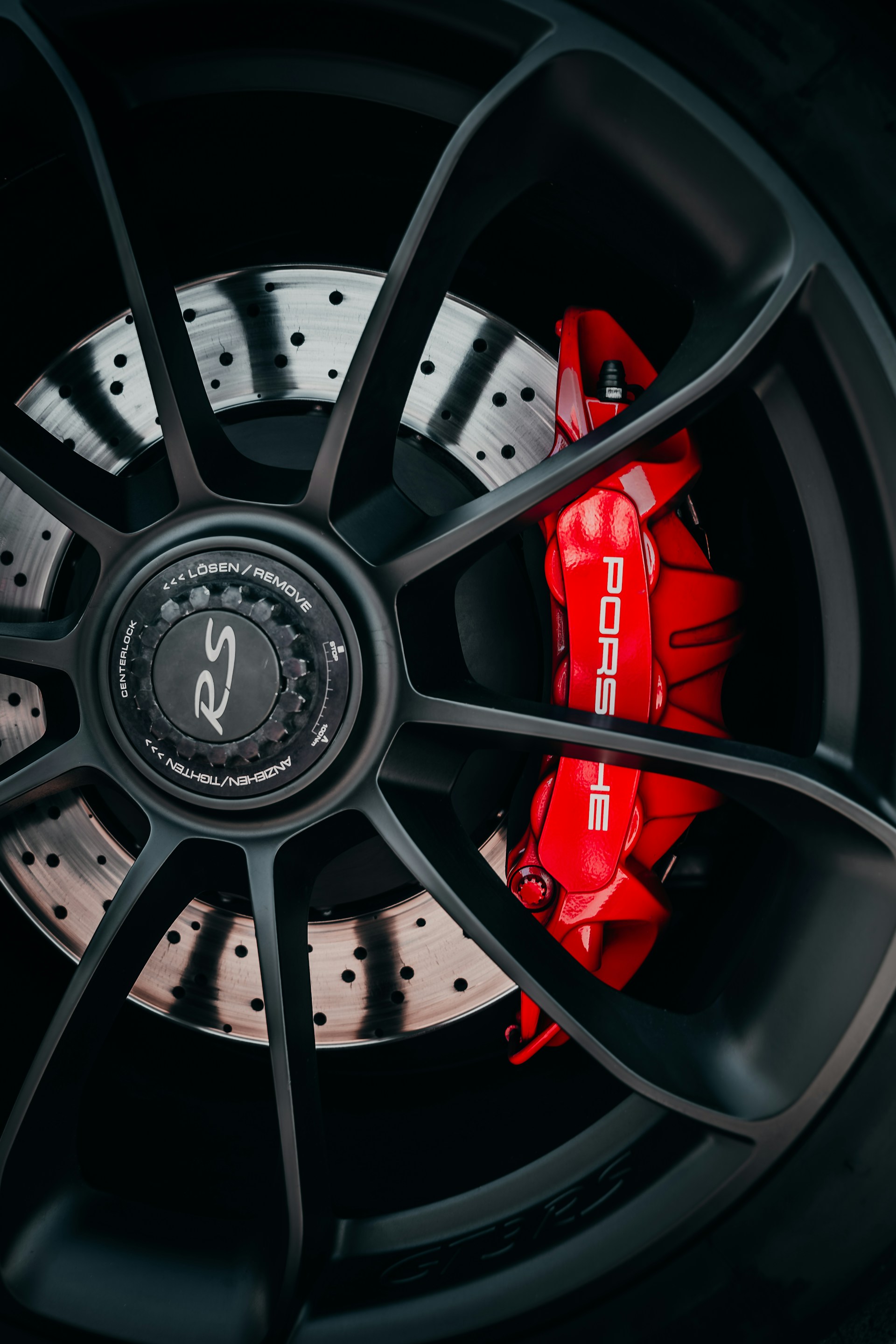 A porsche wheel with striking red brake calipers.