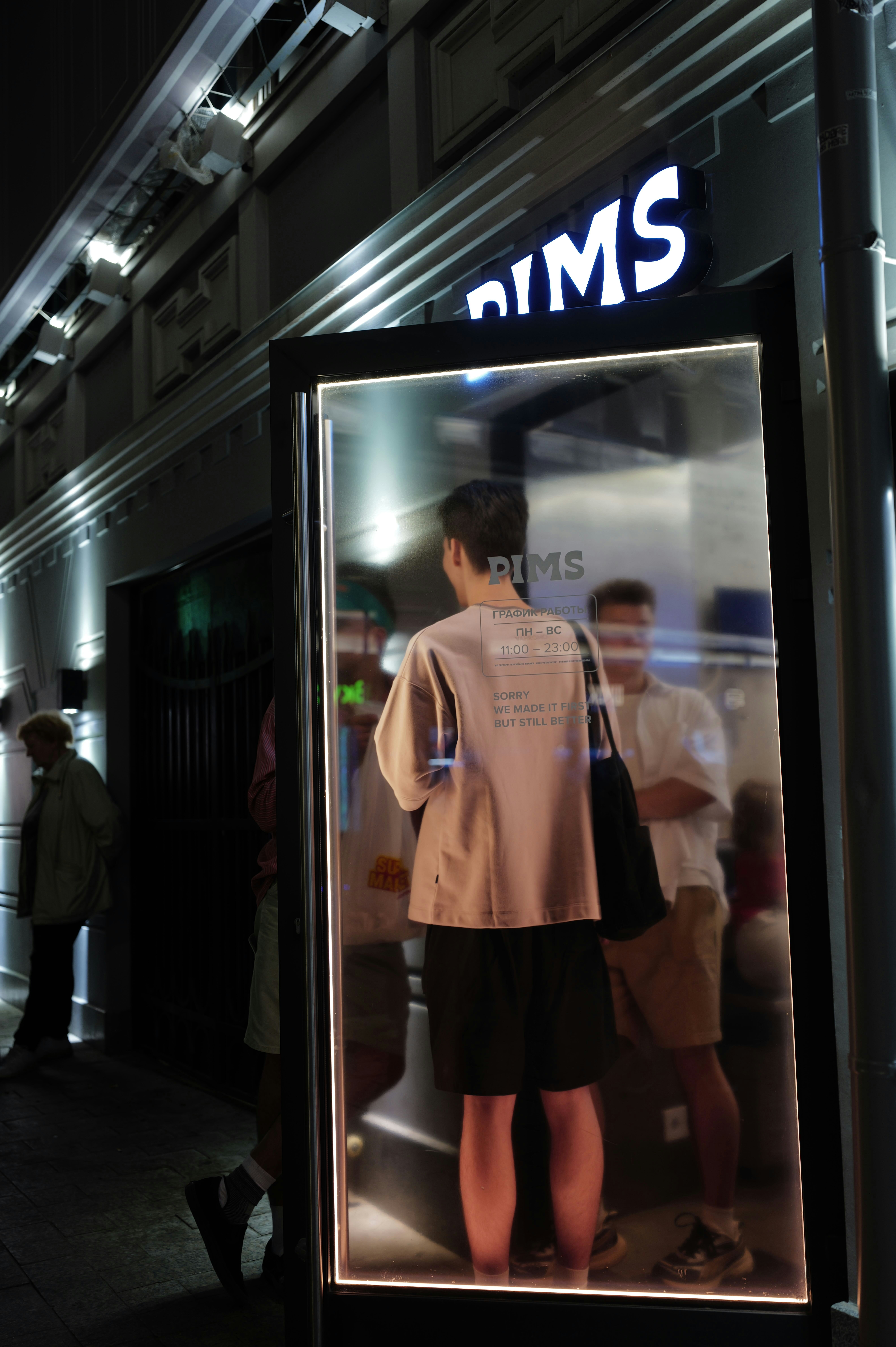 La nuit, des gens se tiennent à l’extérieur d’un restaurant.