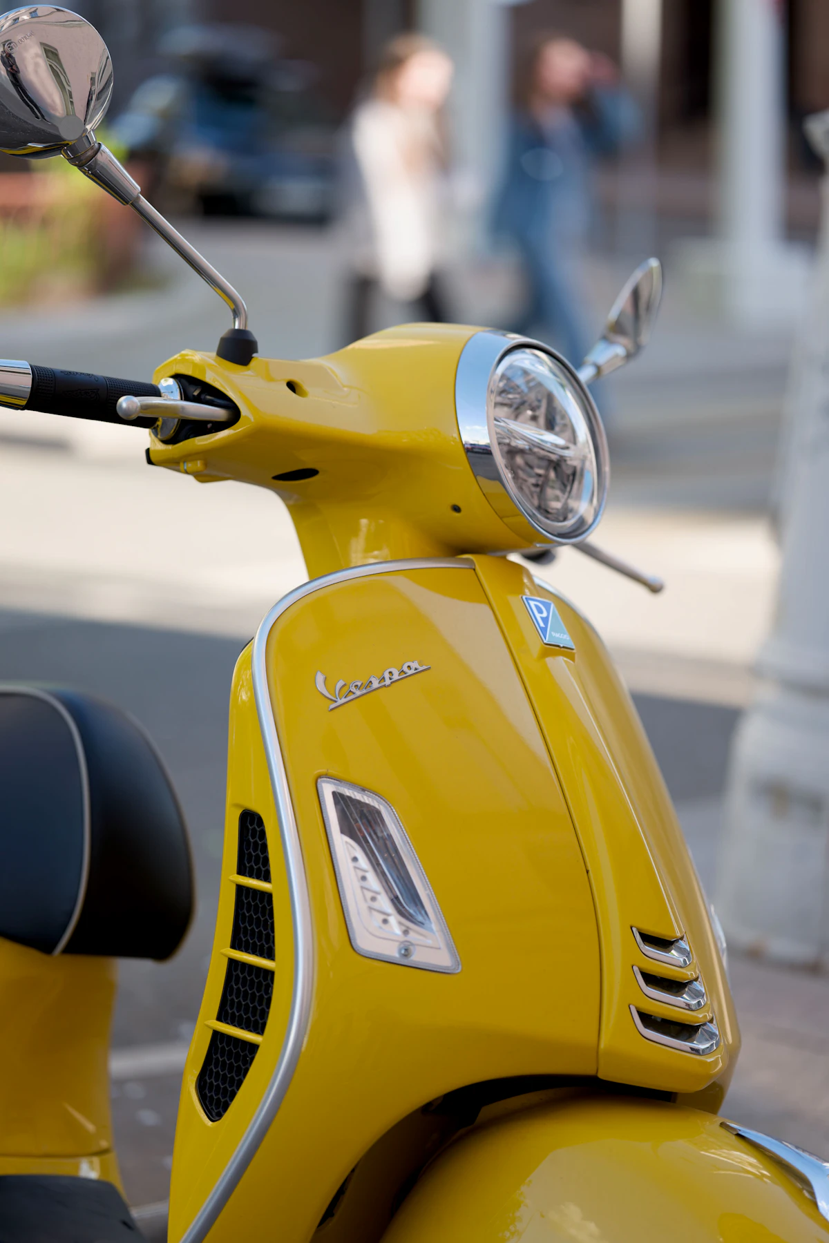 Bright yellow Vespa scooter shown in detail