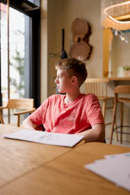 A young boy looks out a window in a cafe.