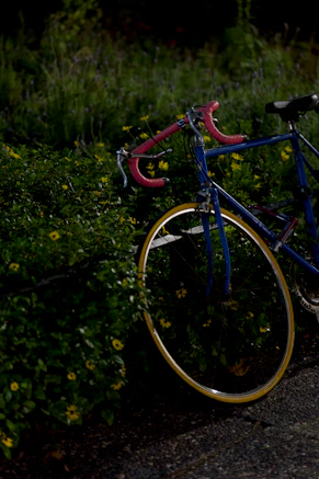 A bicycle is leaning against some green bushes.