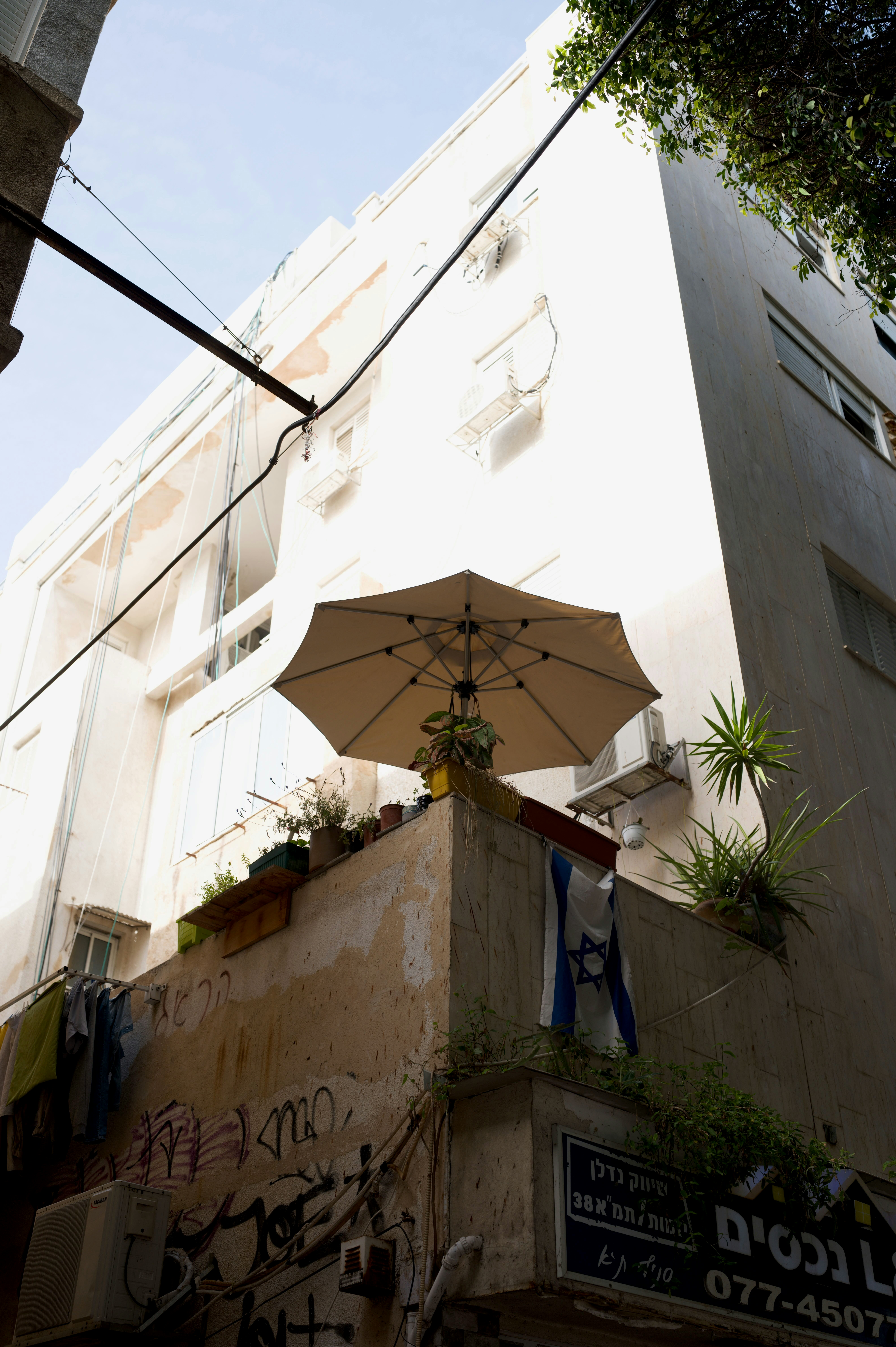 A building with a balcony, umbrella, and plants
