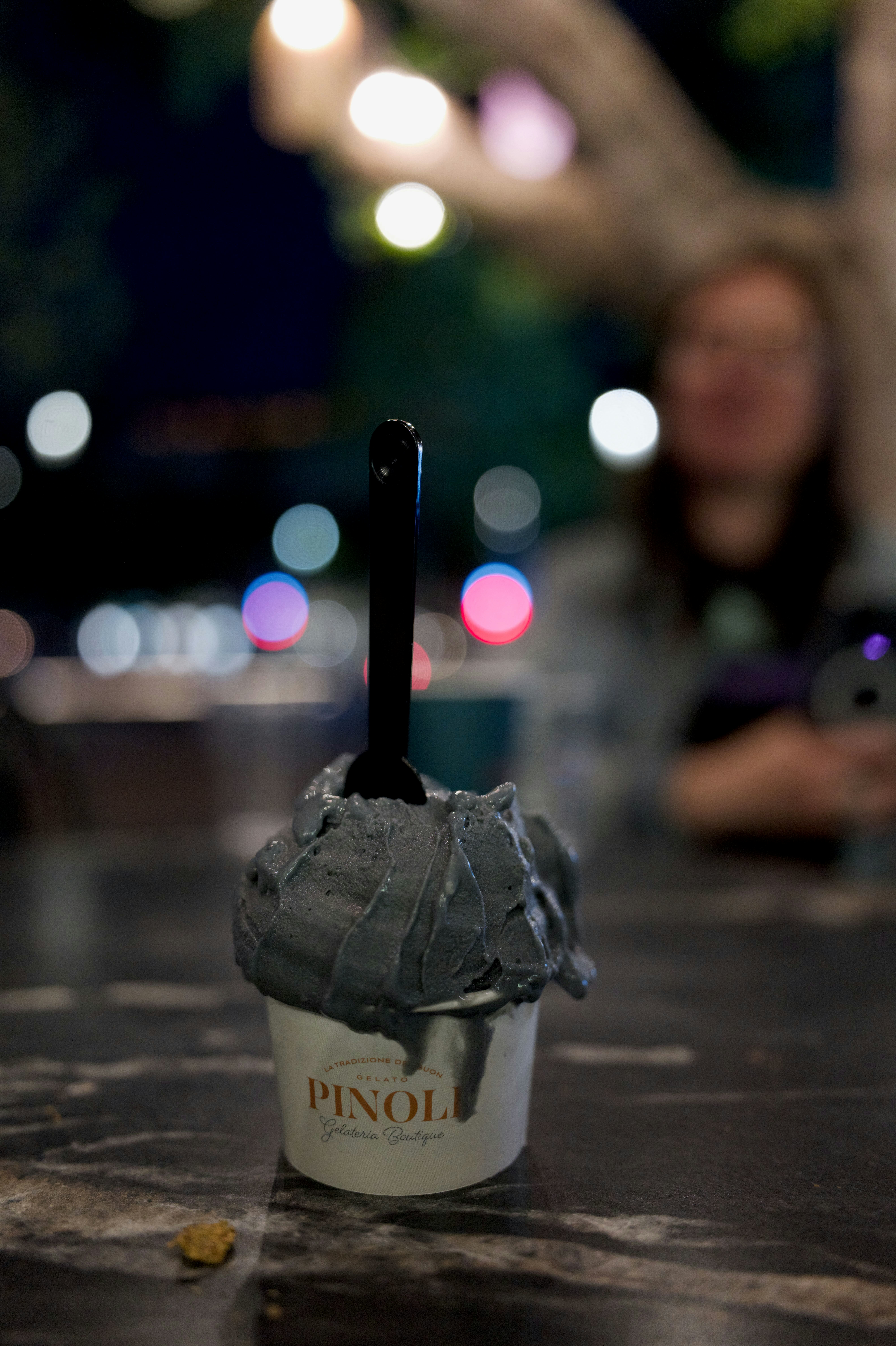 Black gelato in a cup with a blurred background.