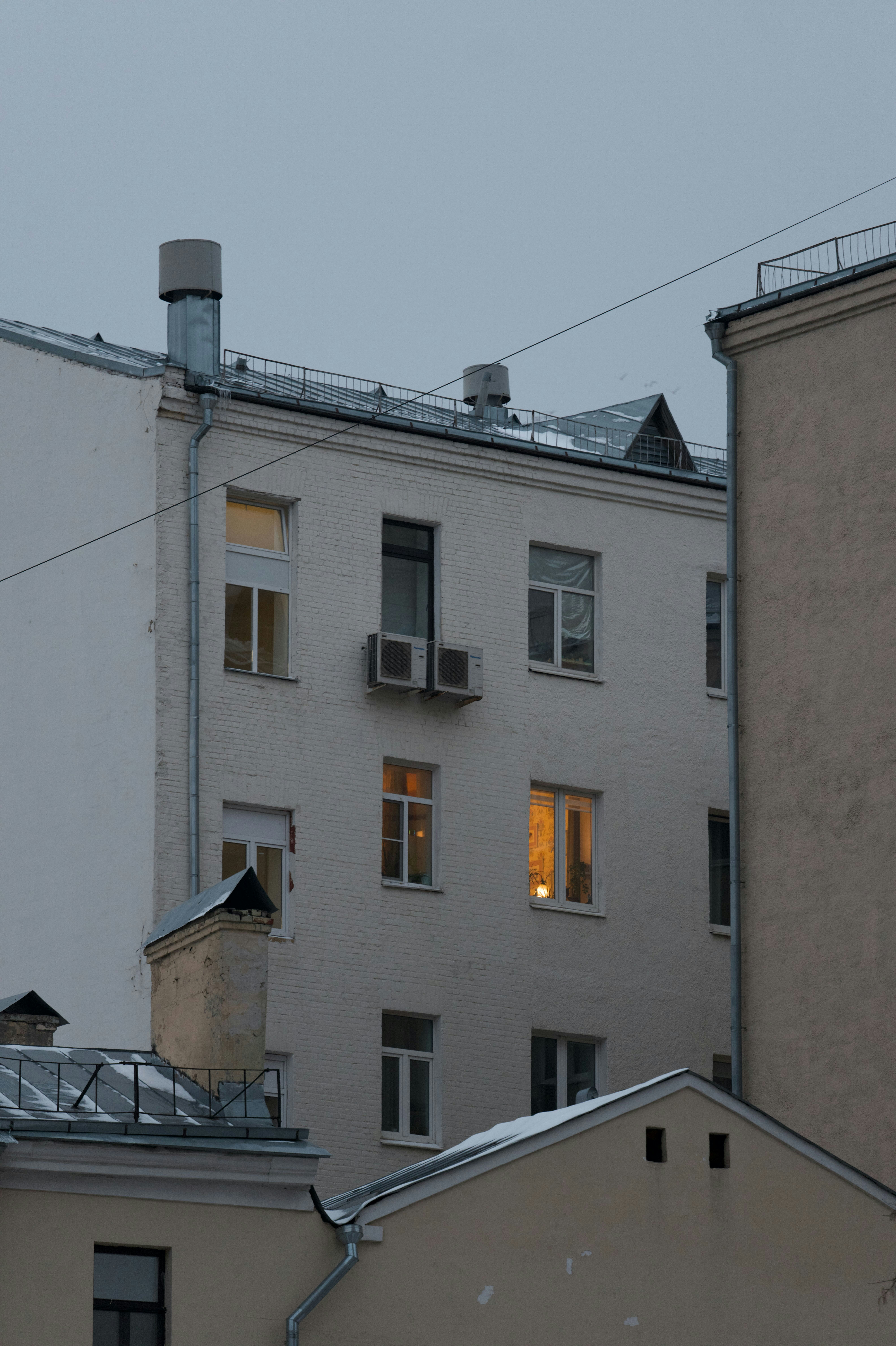 Buildings with lit windows against a gray sky