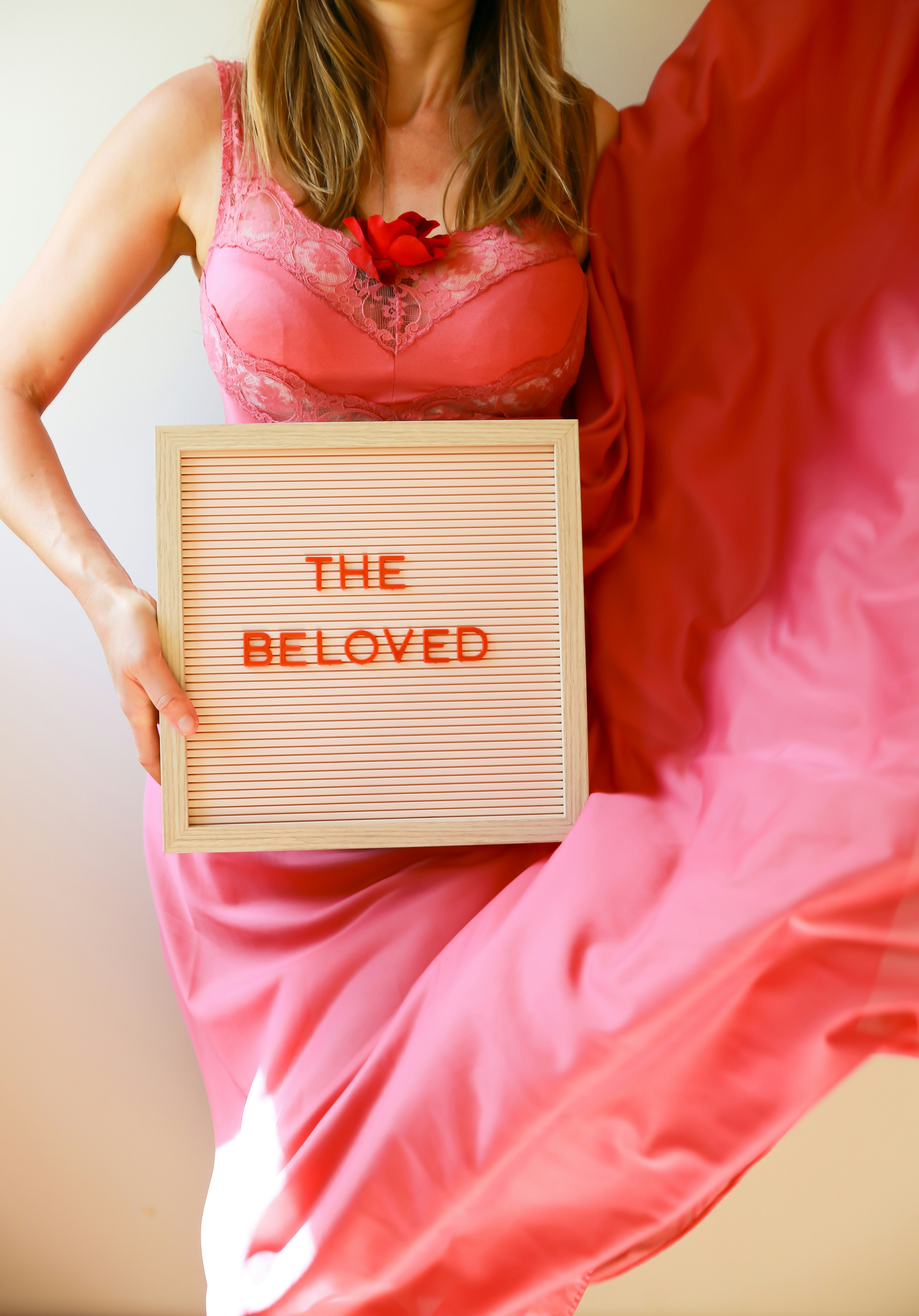 A woman holds a sign that says "the beloved."