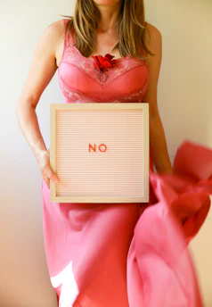 A woman holds a sign that says "no".
