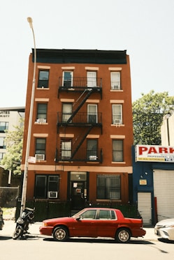 A brick building with a fire escape and car.