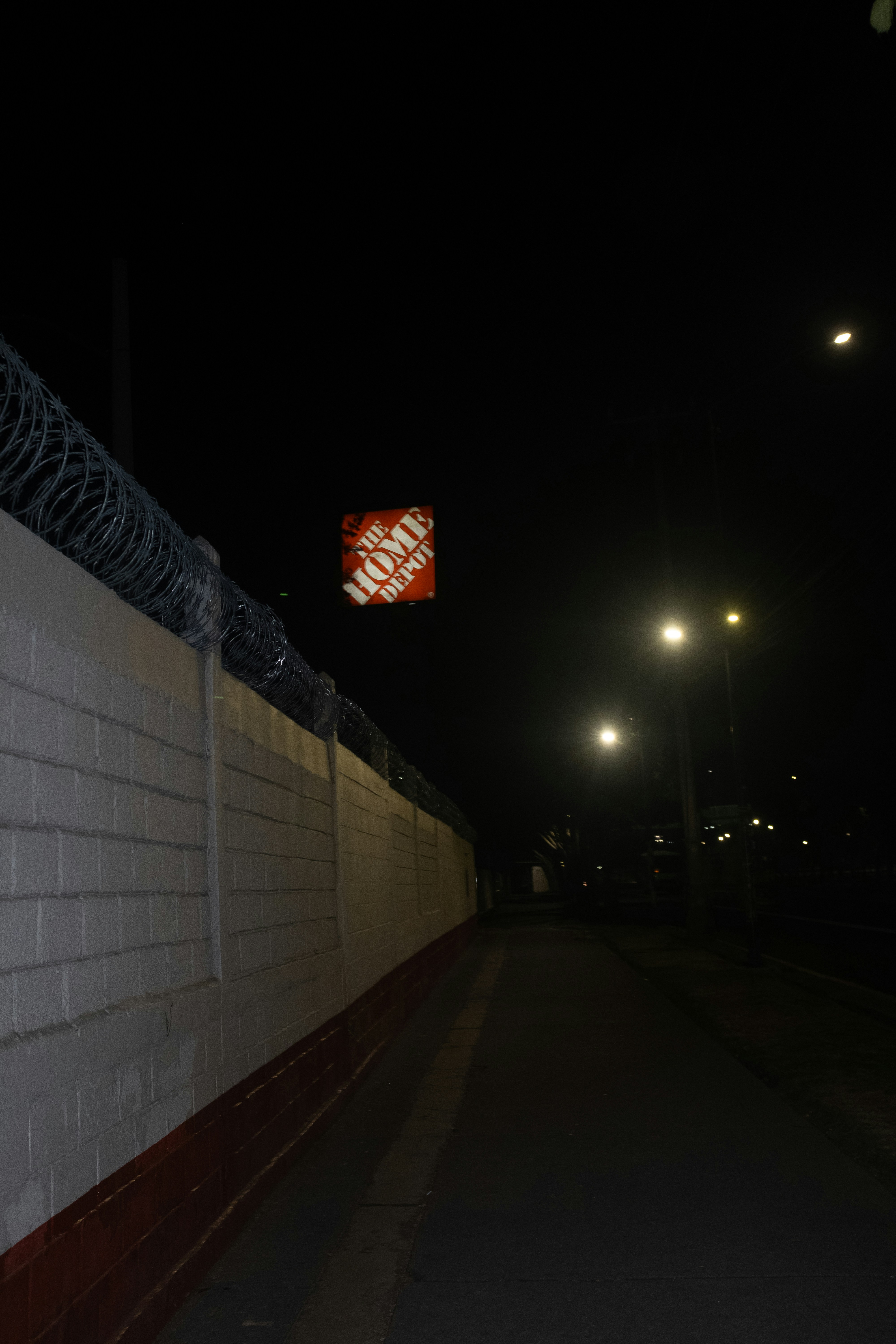 Home depot sign at night next to a wall.