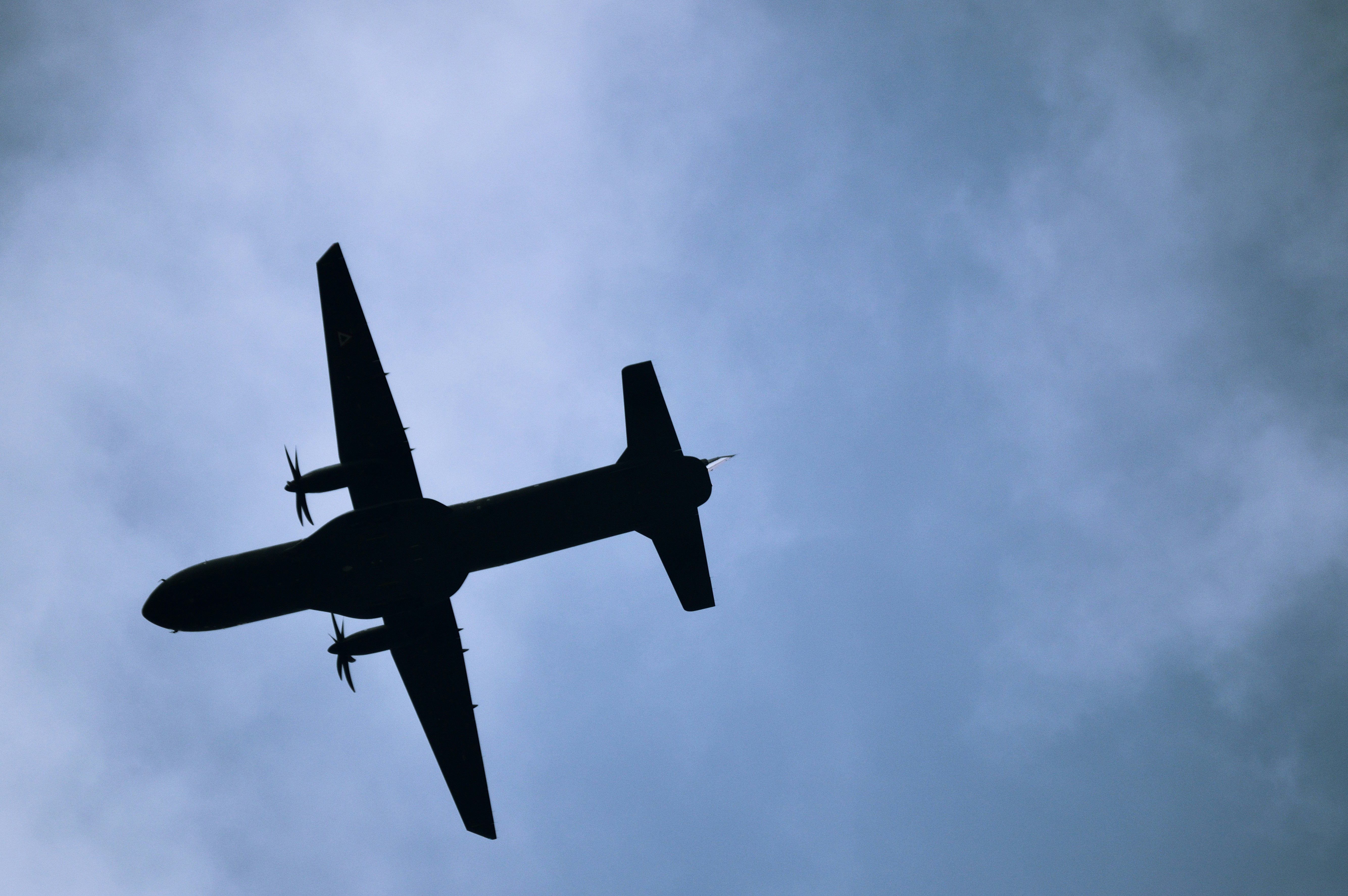 A silhouette of a plane flies across the sky.