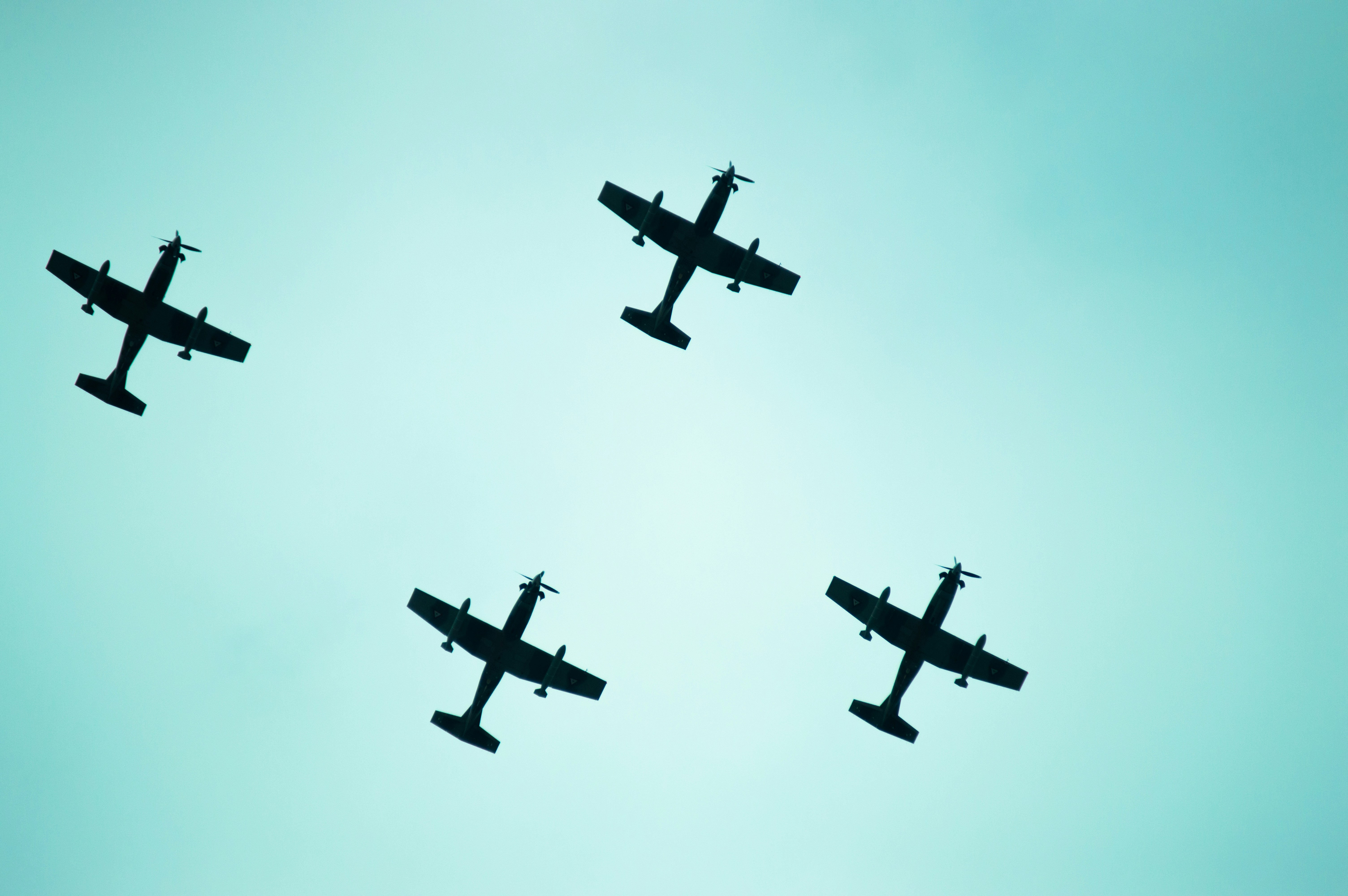 Four airplanes fly silhouetted against the sky.