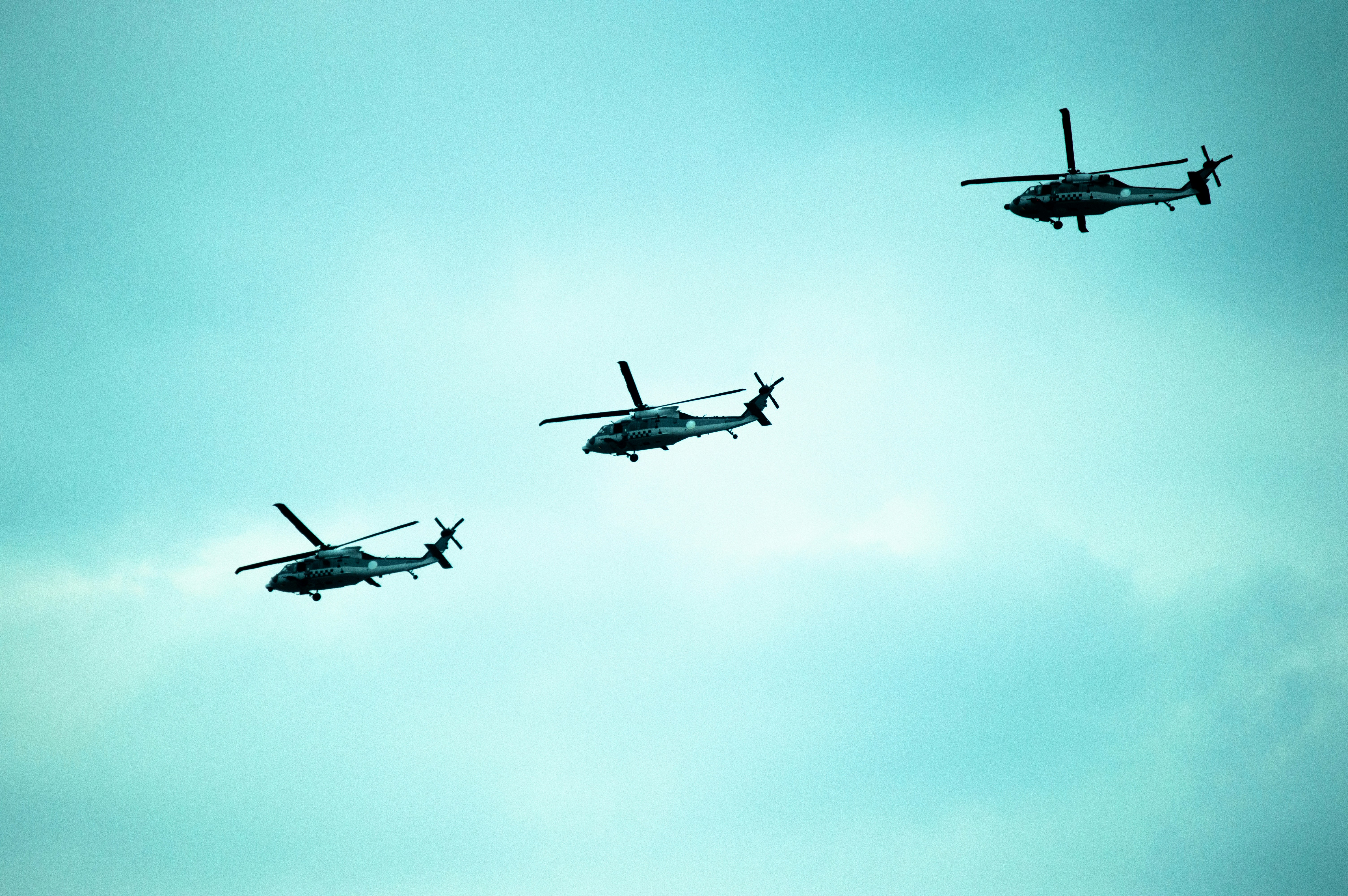 Three helicopters fly in the sky.