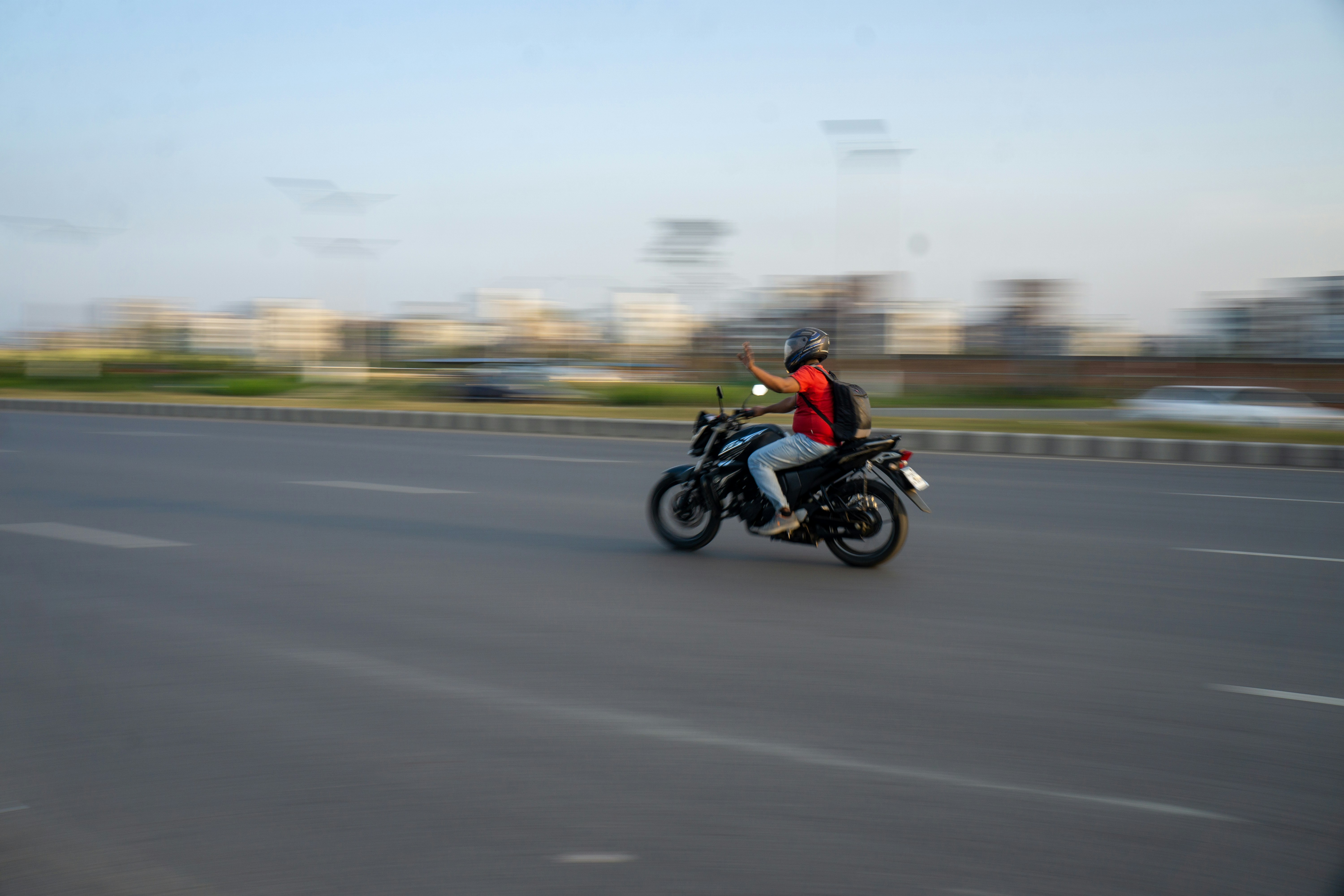 El motociclista circula por una carretera larga y abierta.