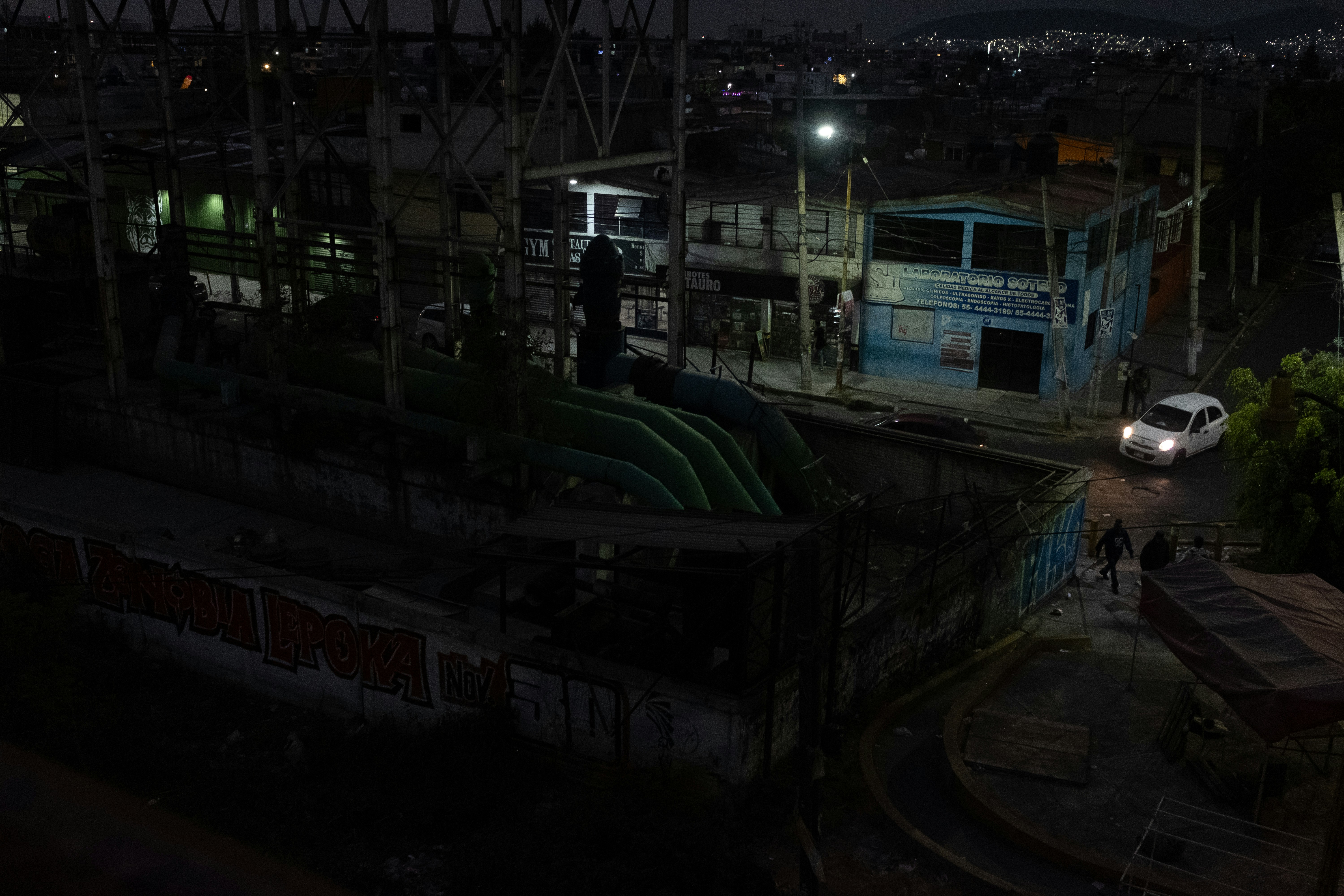 Nighttime view of industrial structures and a car.