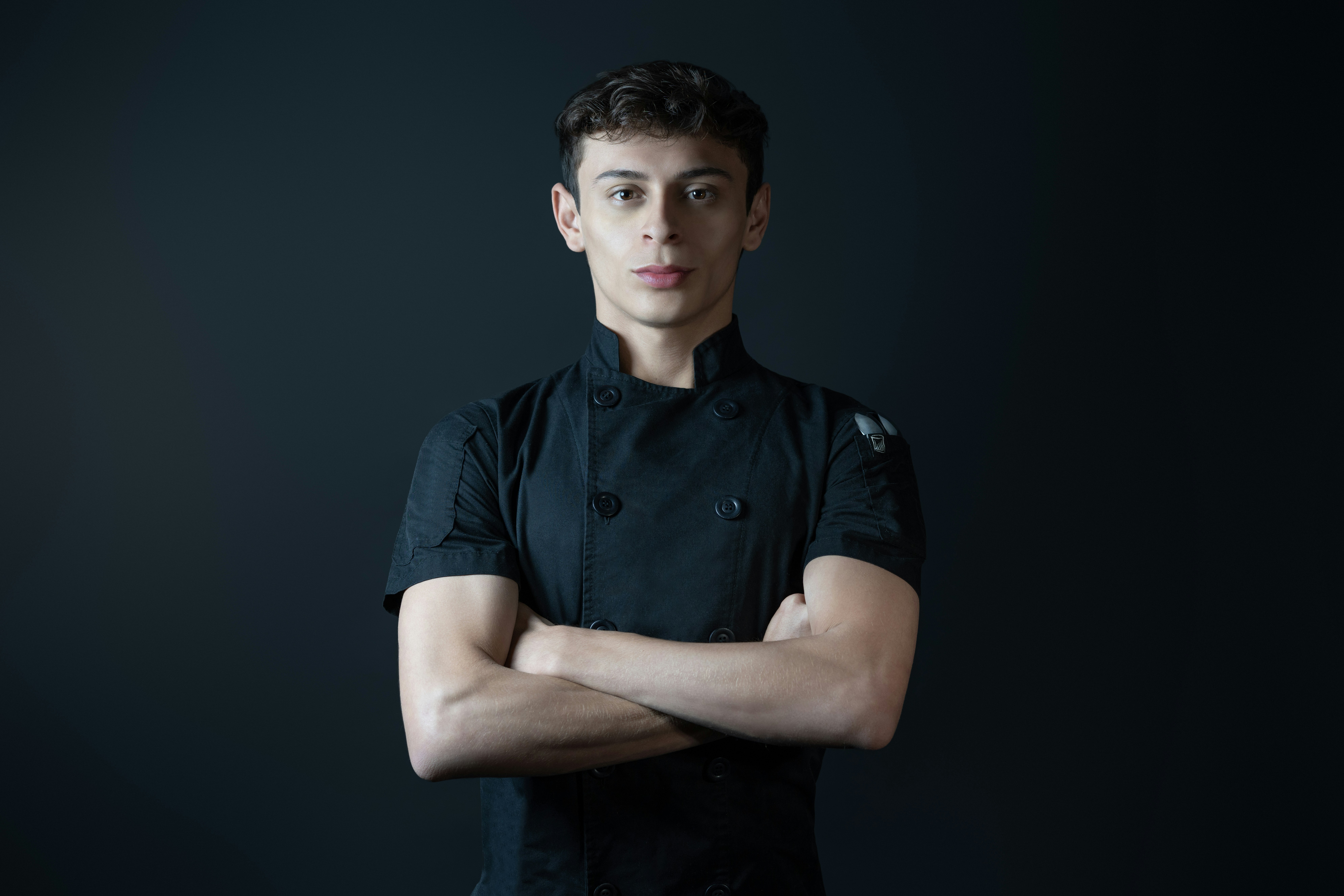 A chef poses with arms crossed.