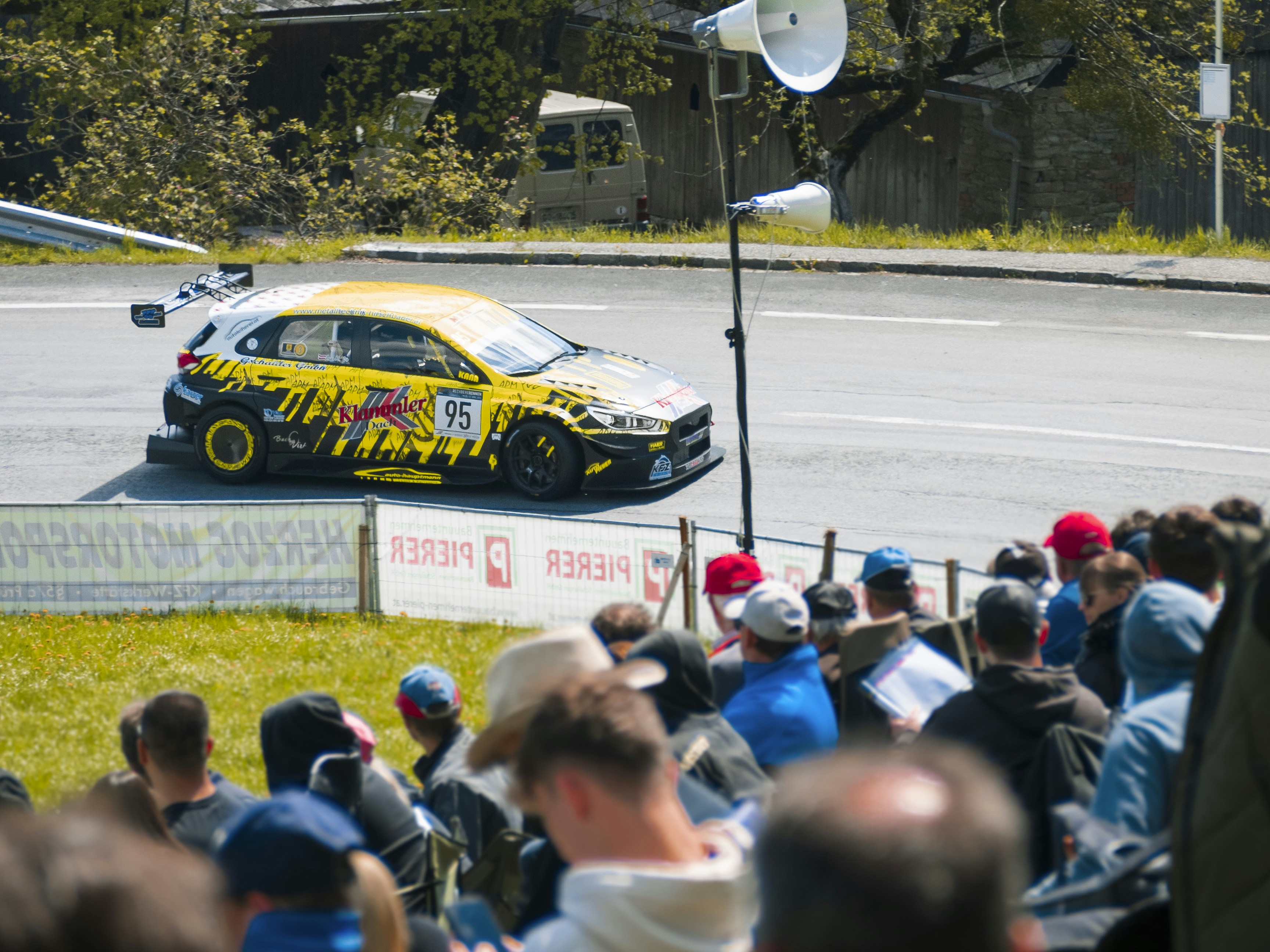 Race car speeds past crowds of spectators.