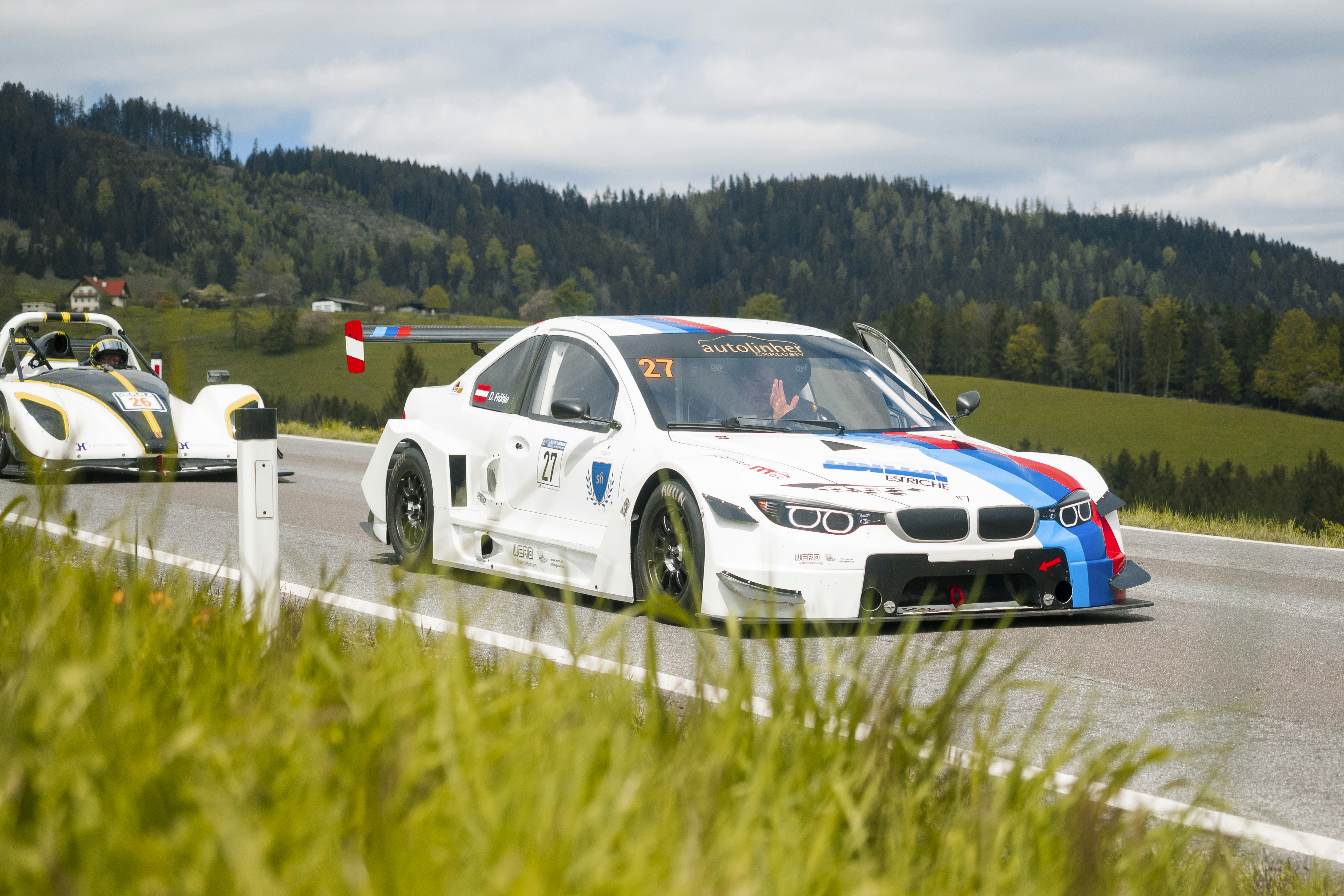 A racing BMW car speeds along a road.