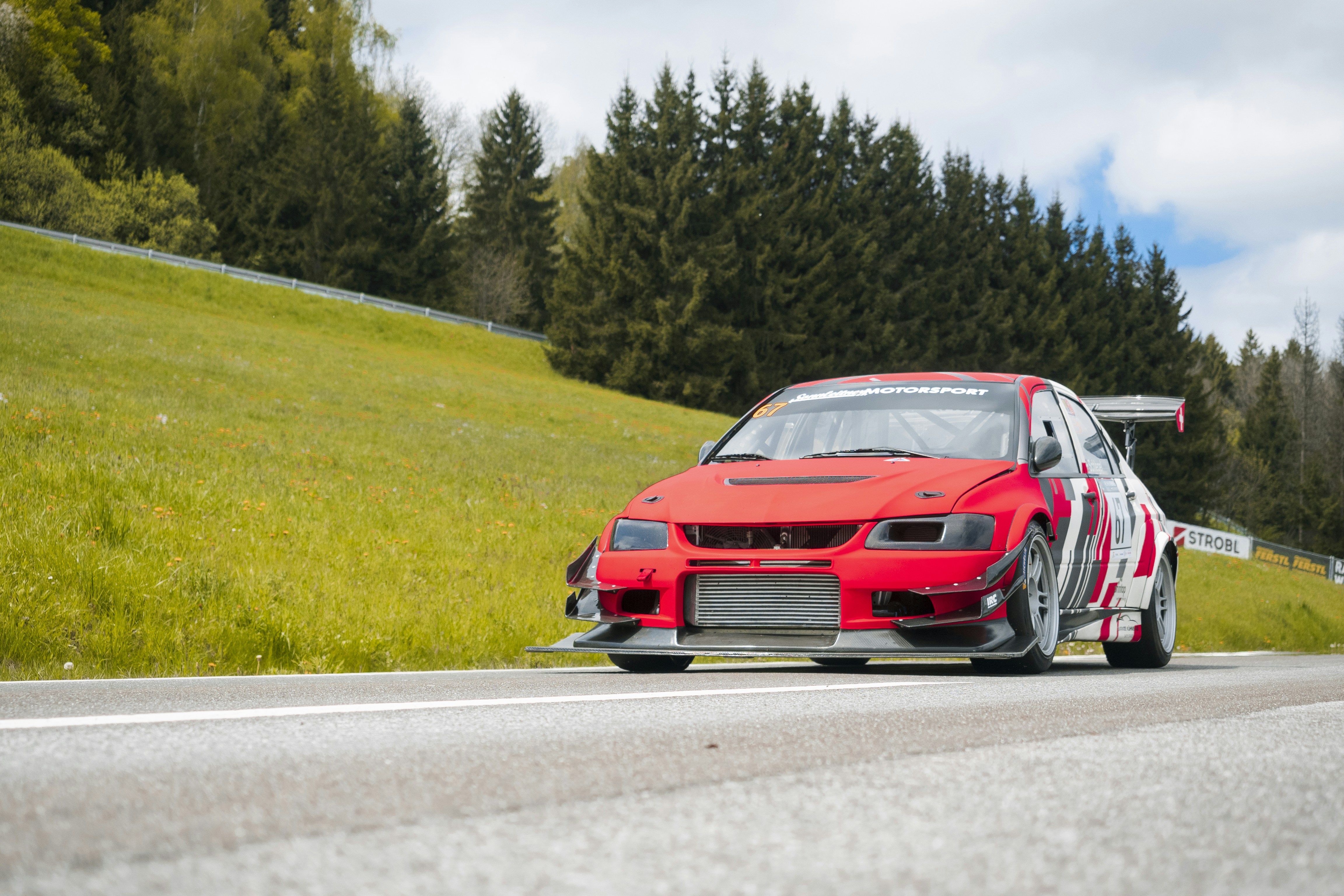 A red race car speeds down the road.