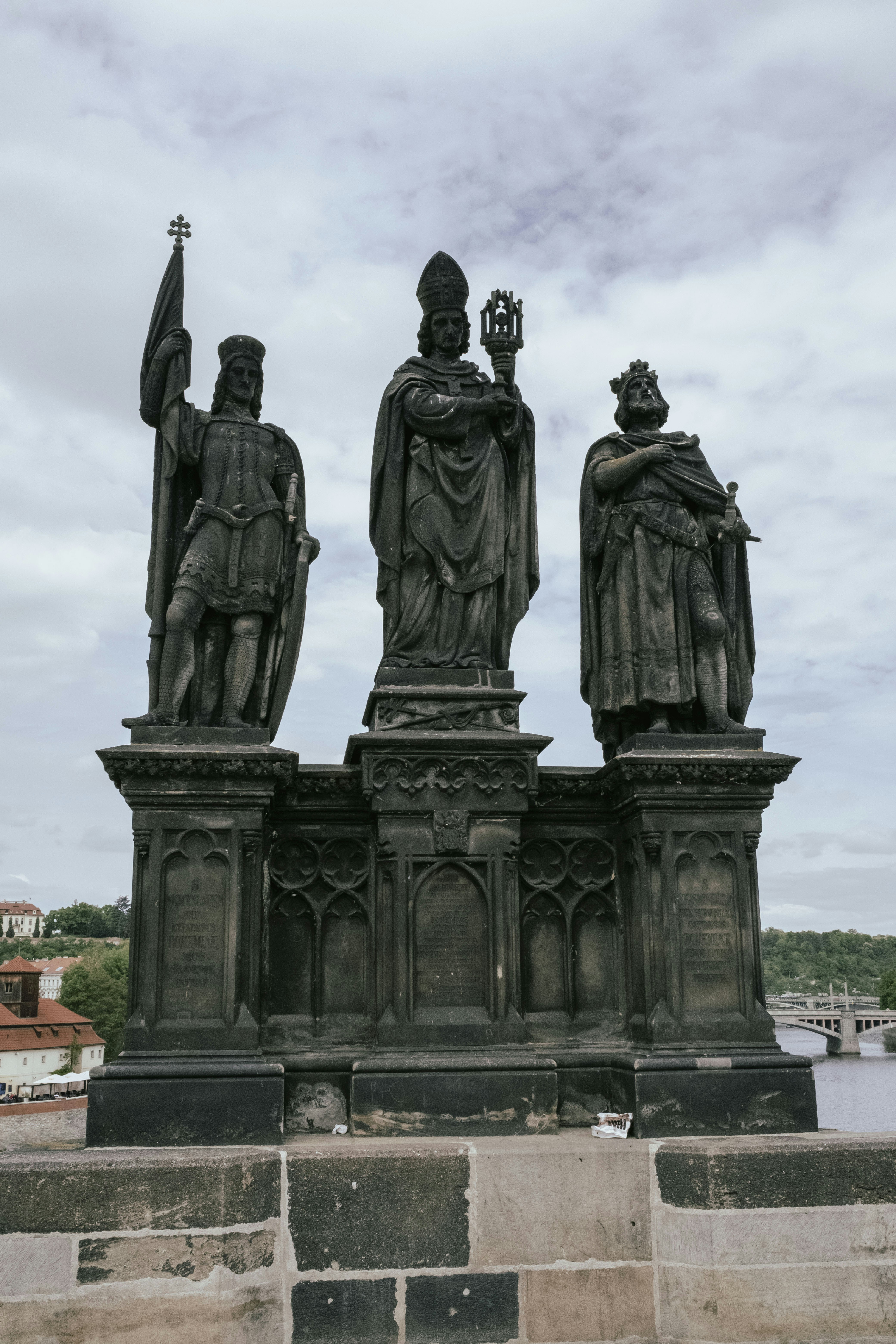 Statues stand on a bridge under a cloudy sky.