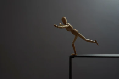 A wooden mannequin is about to fall.