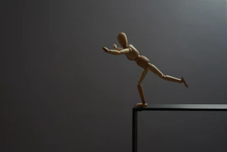 A wooden mannequin is about to fall.