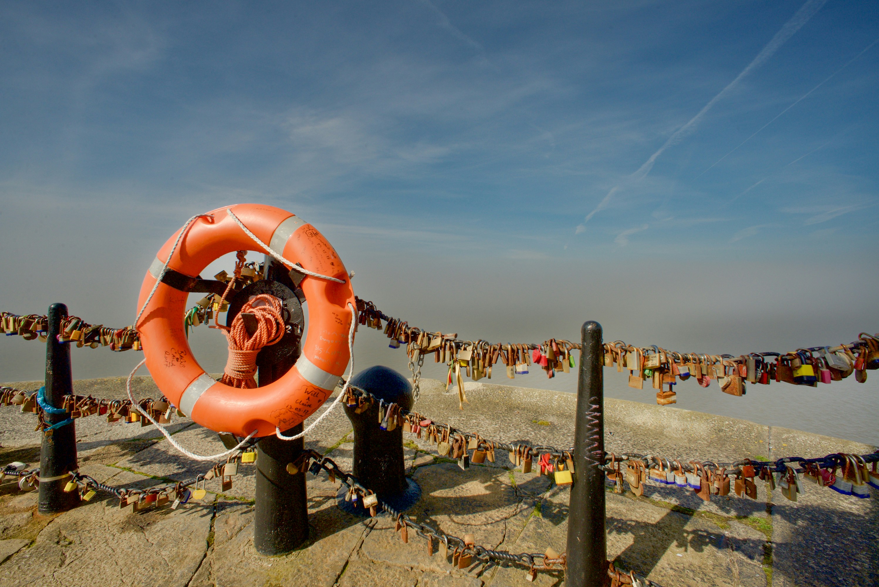 A life preserver and love locks against a hazy sky.