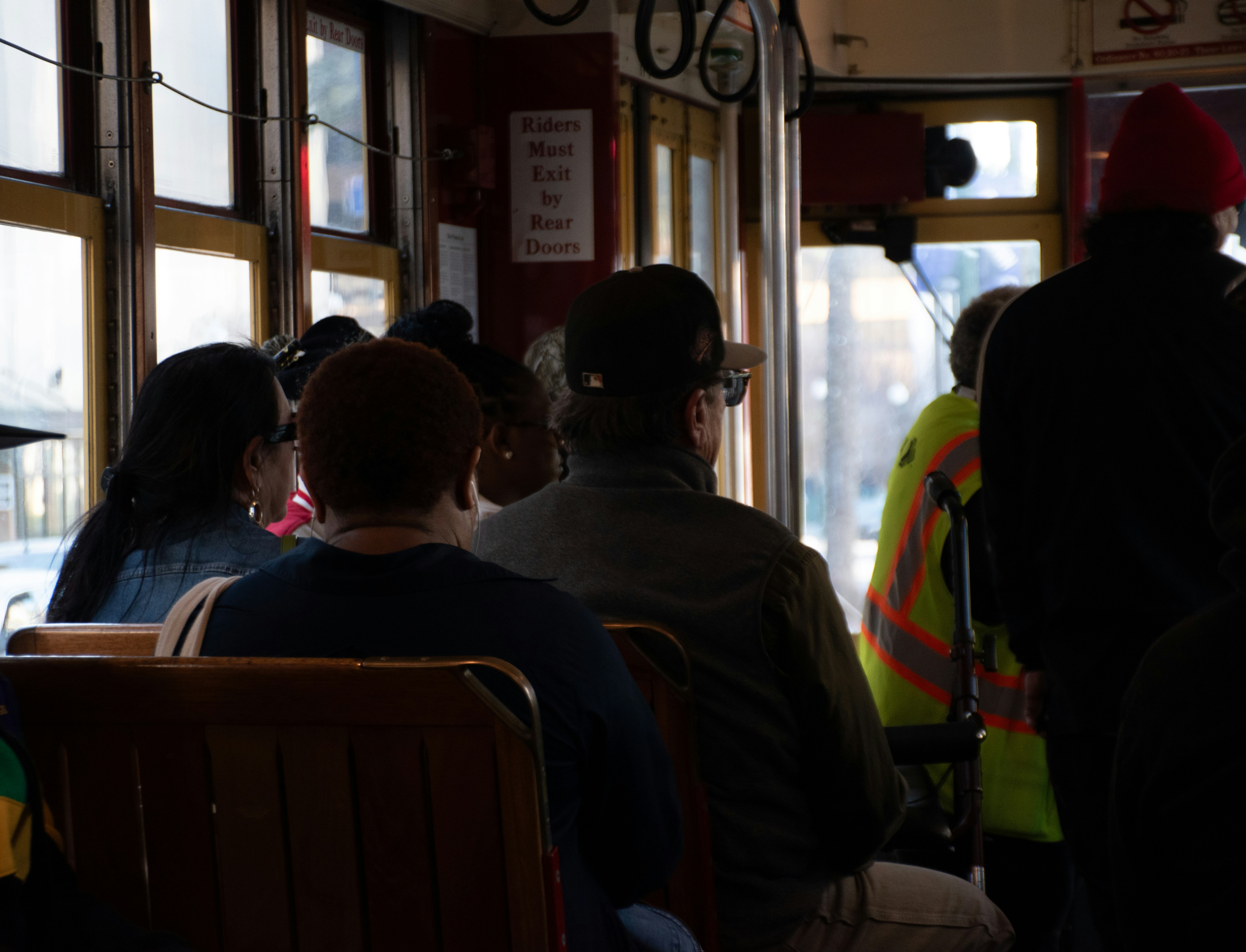 People ride a trolley car, facing forward.