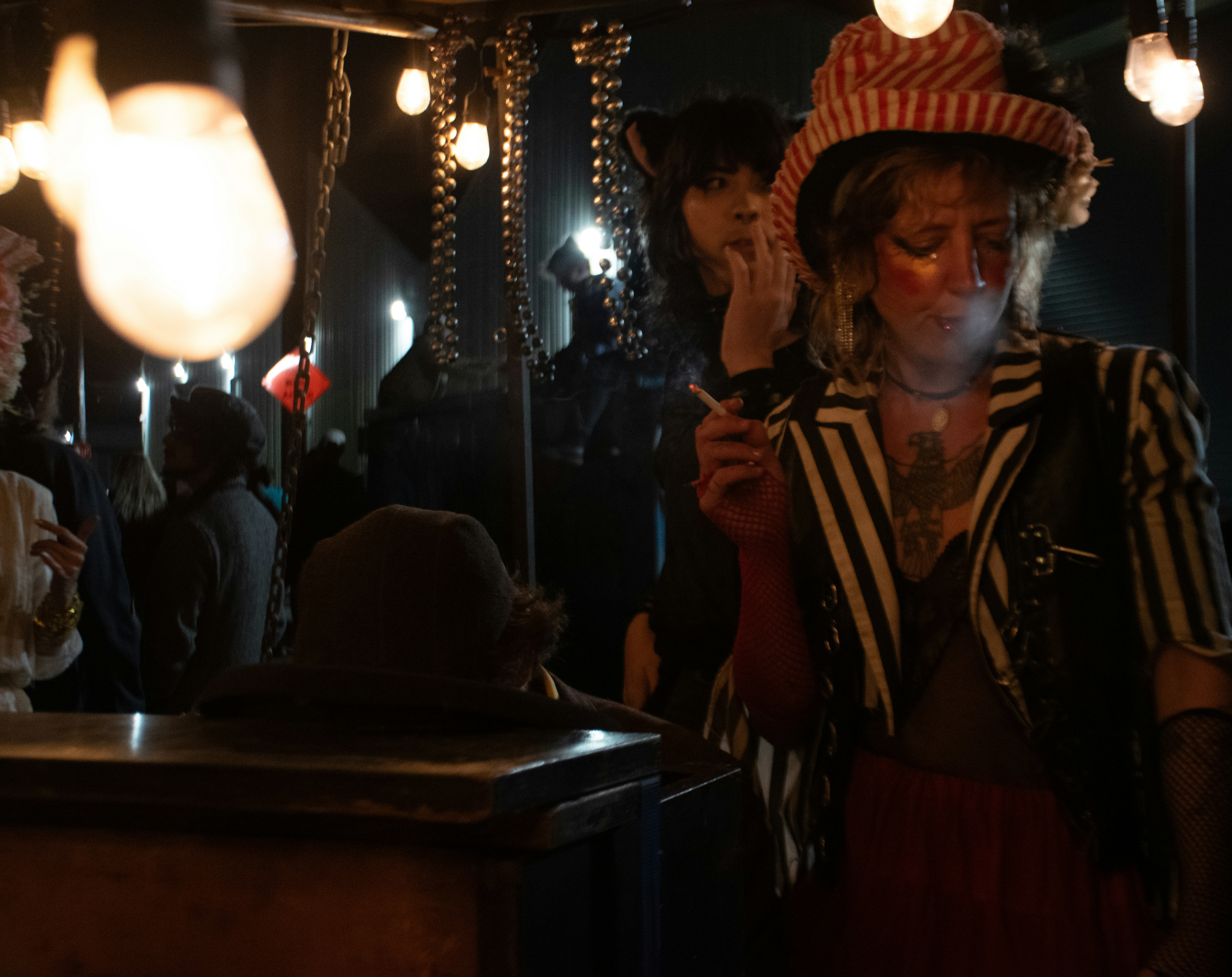 A woman smokes in a dark, theatrical setting.