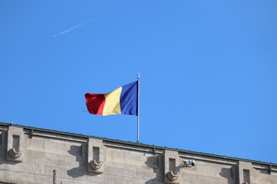 The romanian flag waves proudly against a clear sky.