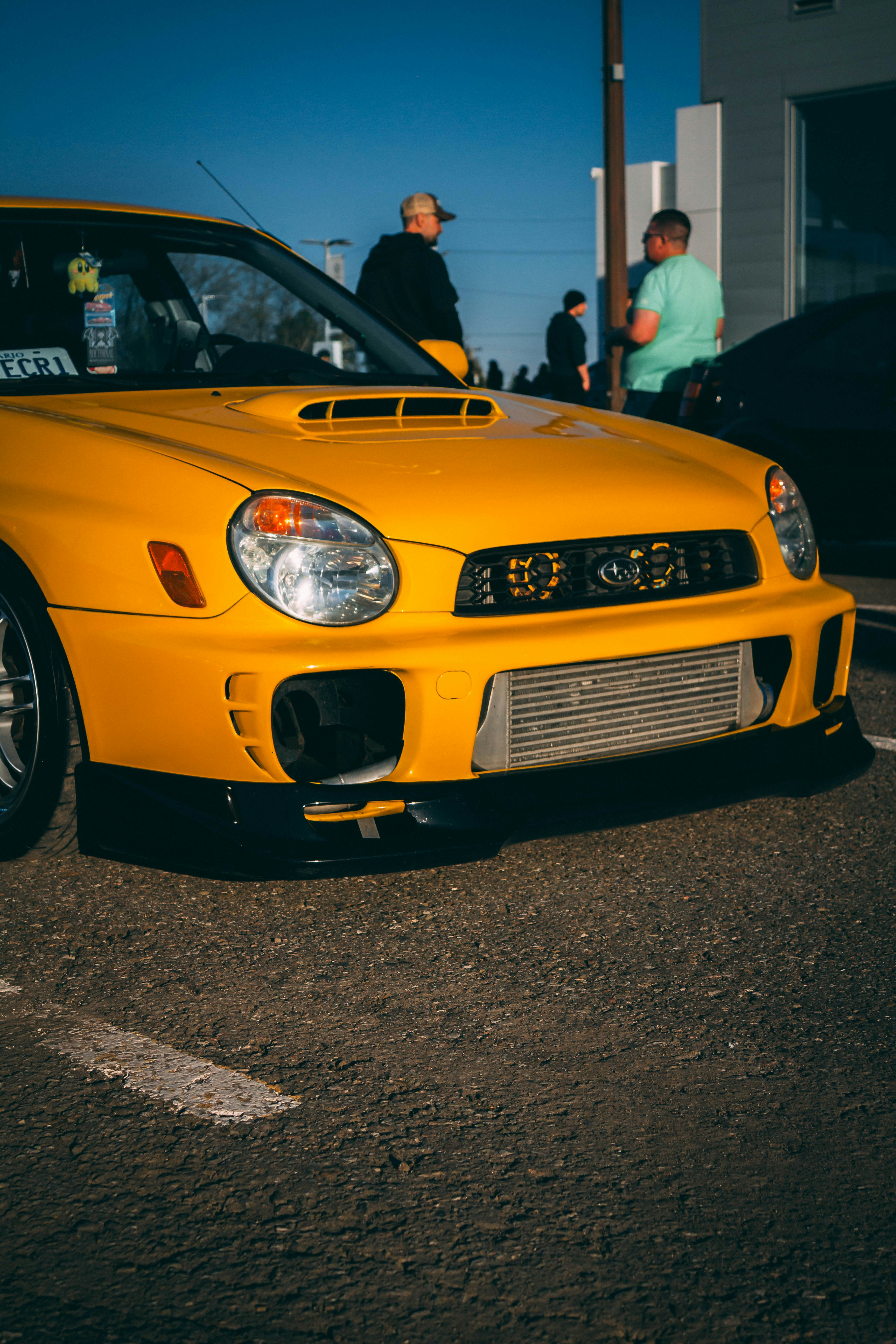 A bright yellow car sits parked in the sun.