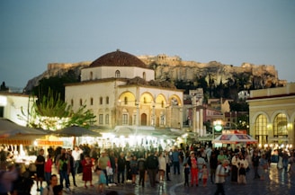 A crowd gathers in athens, with acropolis in view.