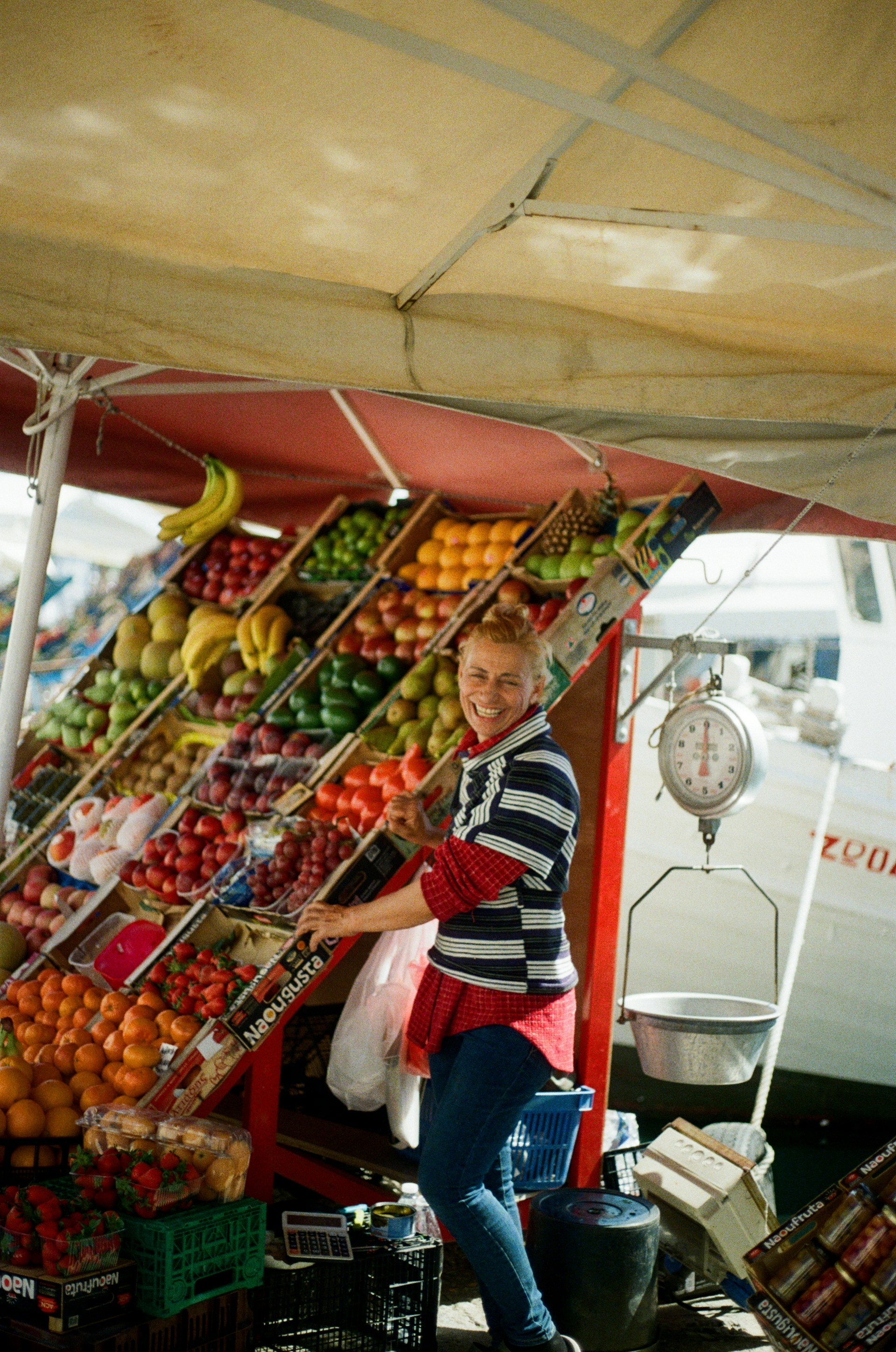 A smiling vendor sells fresh fruit at her stall.