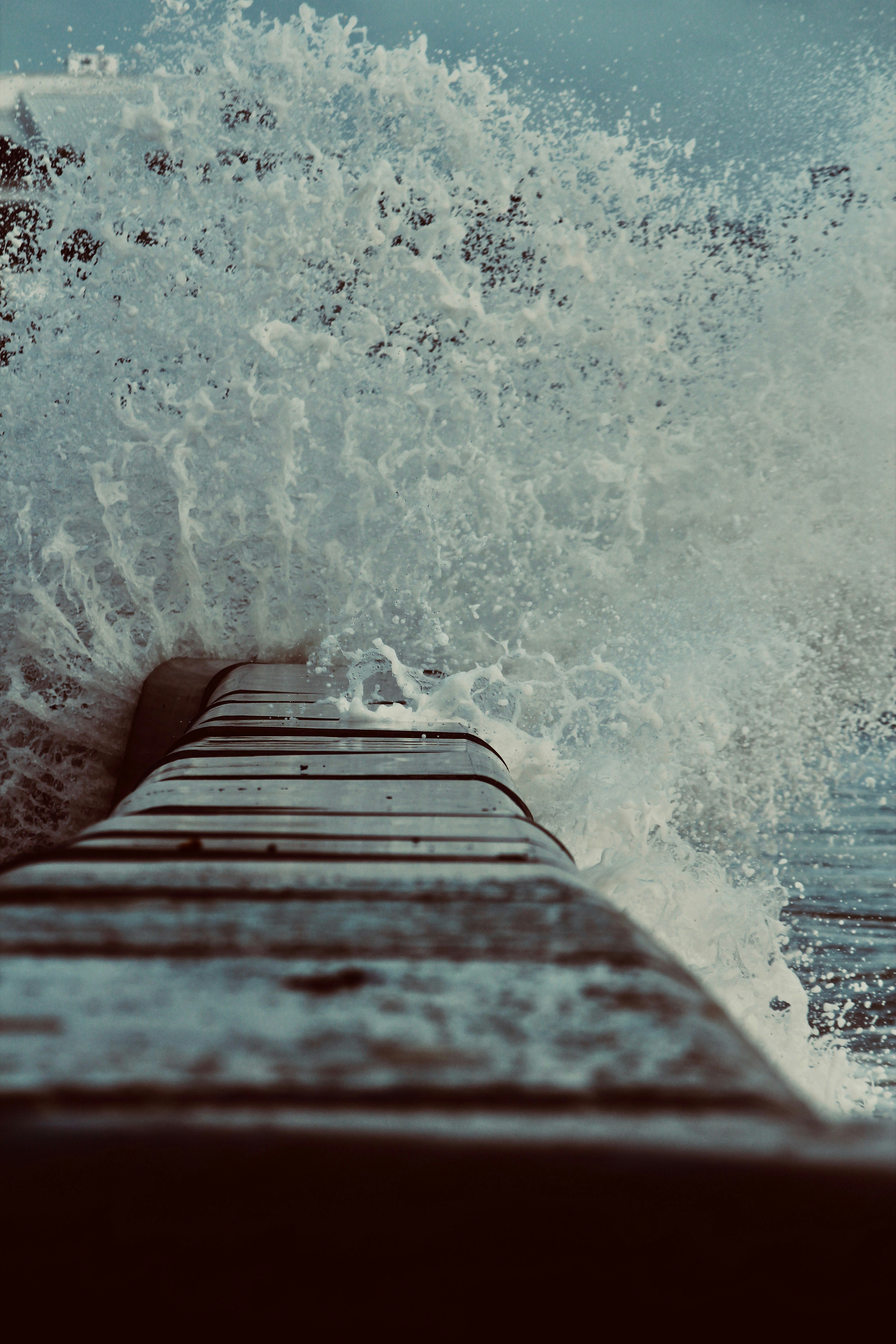 A wave crashes against a wooden dock.
