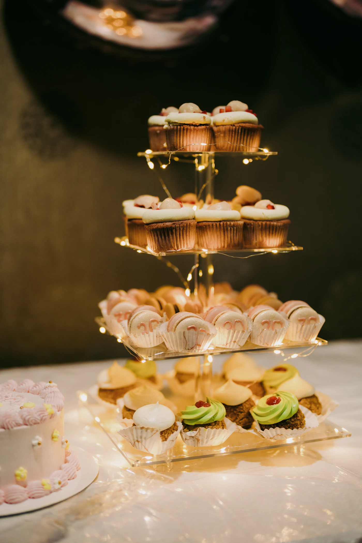 Wedding cake alternatives for small budgets — A tiered cupcake display with pastel frosting at a rustic barn reception.