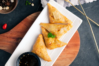 Crispy golden samosas served with dipping sauce