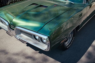 A green vintage car's front side is shown.