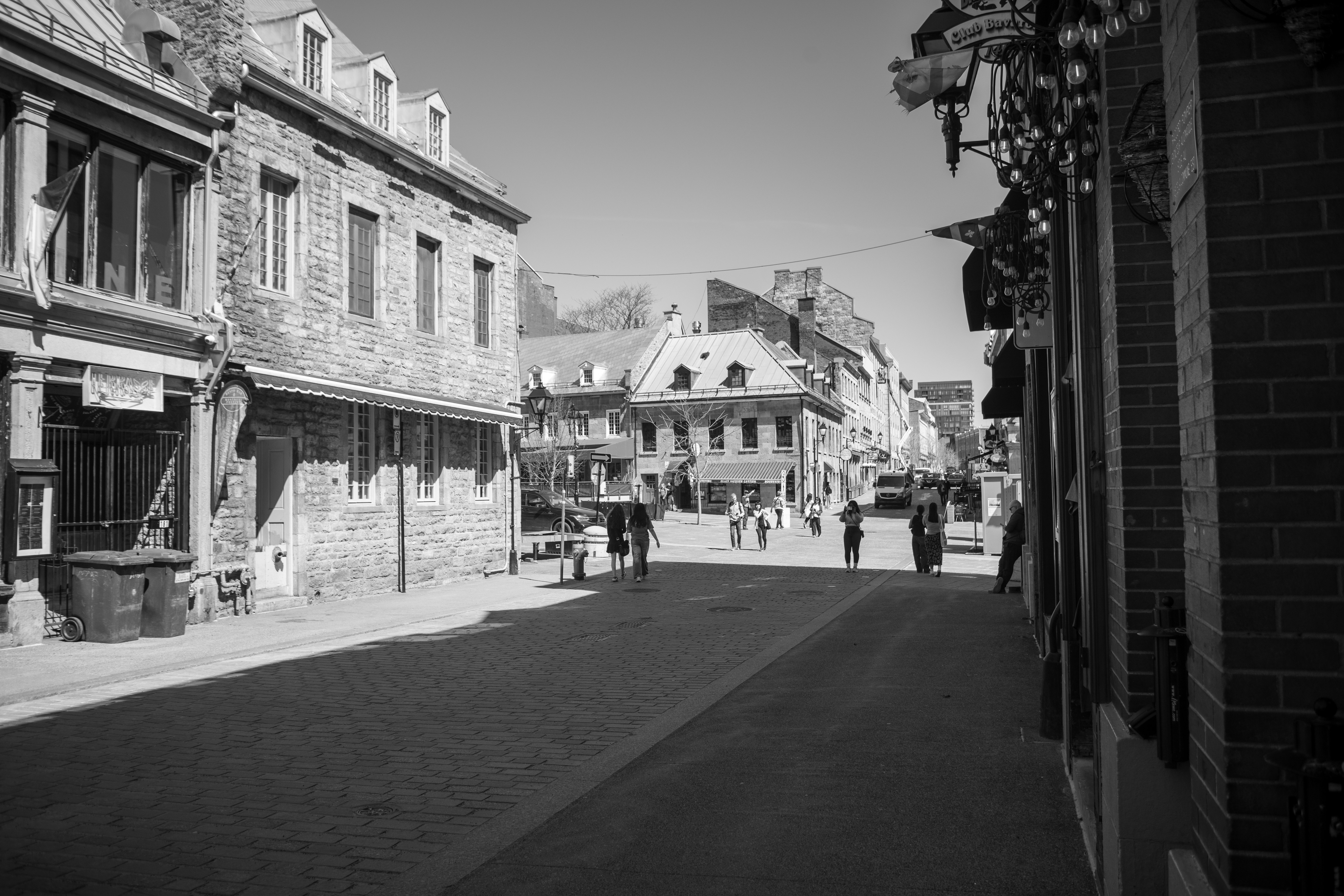 Old stone buildings line a quiet, sunny street.