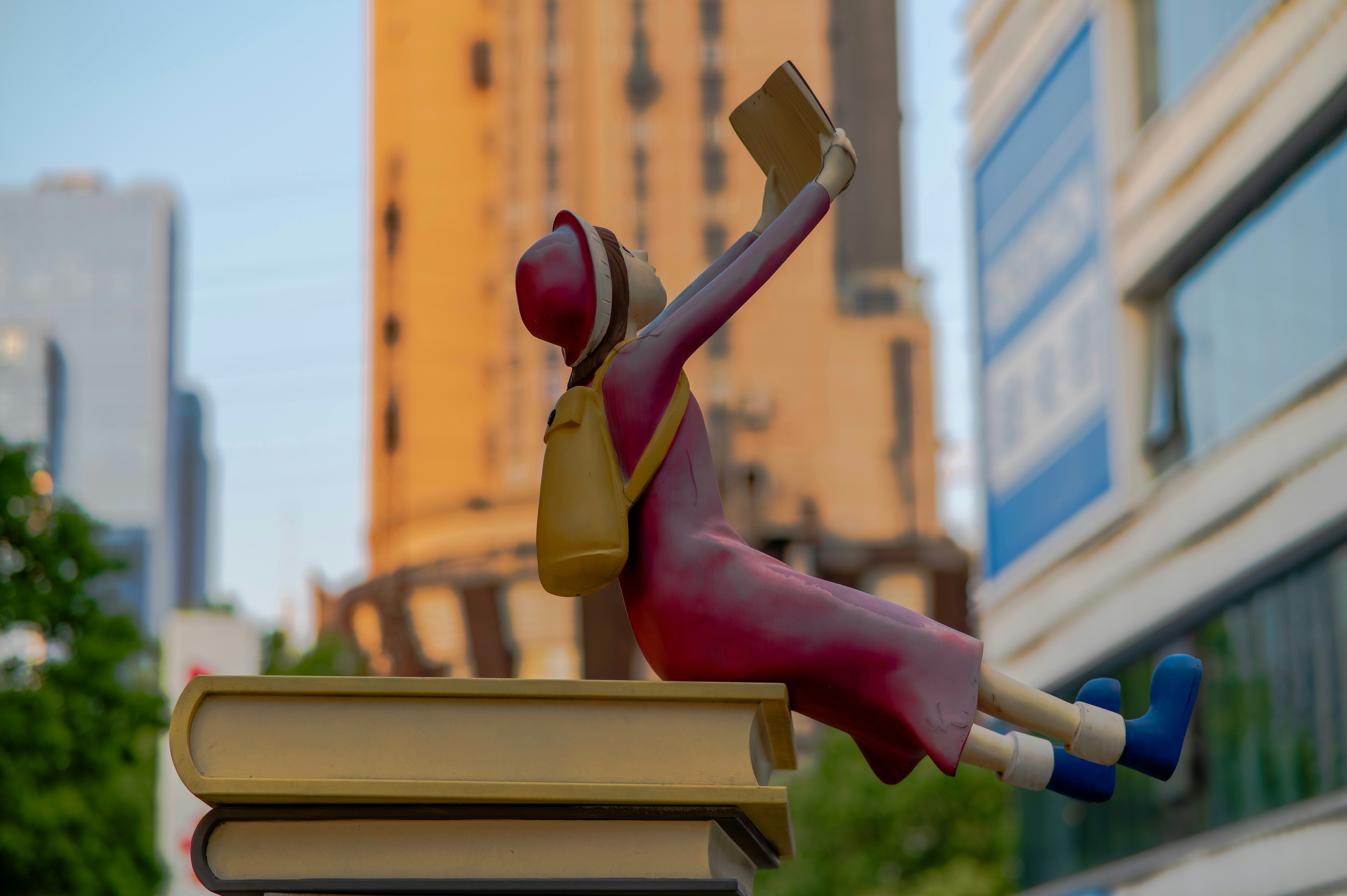 Statue of a person reading atop books in the city.