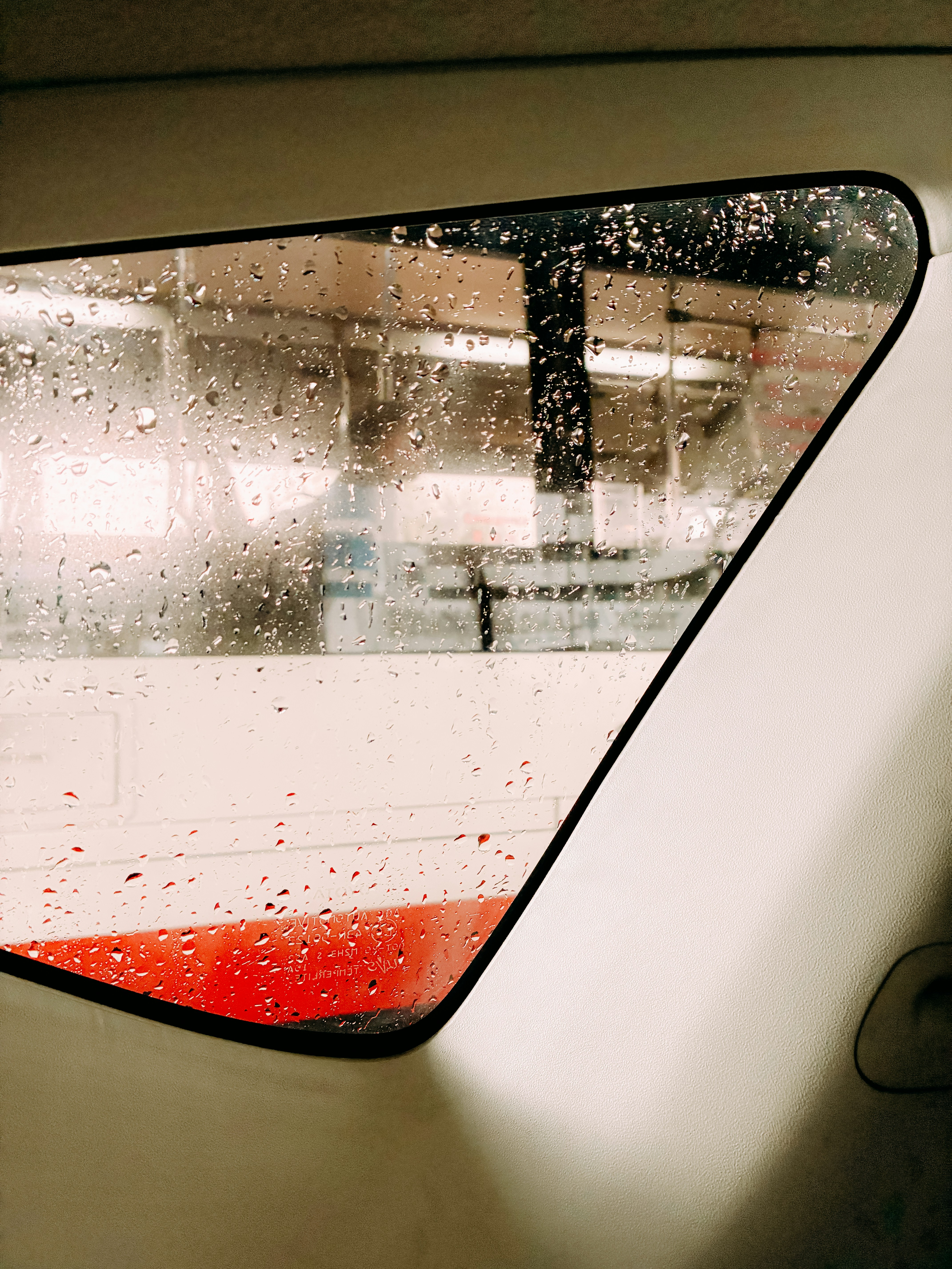 Raindrops on a window show a blurry view.