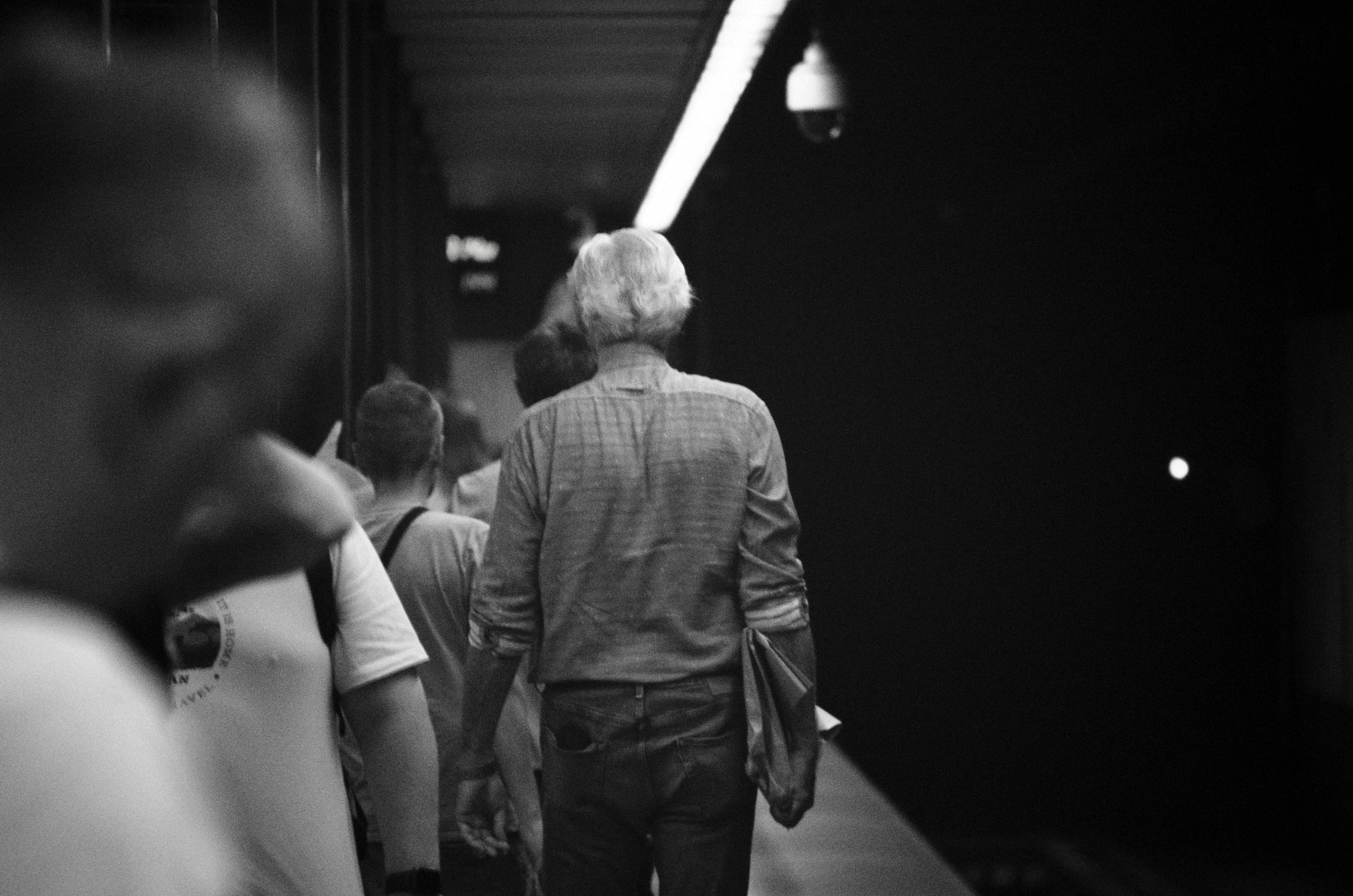 People walk in a dim, long, interior space.