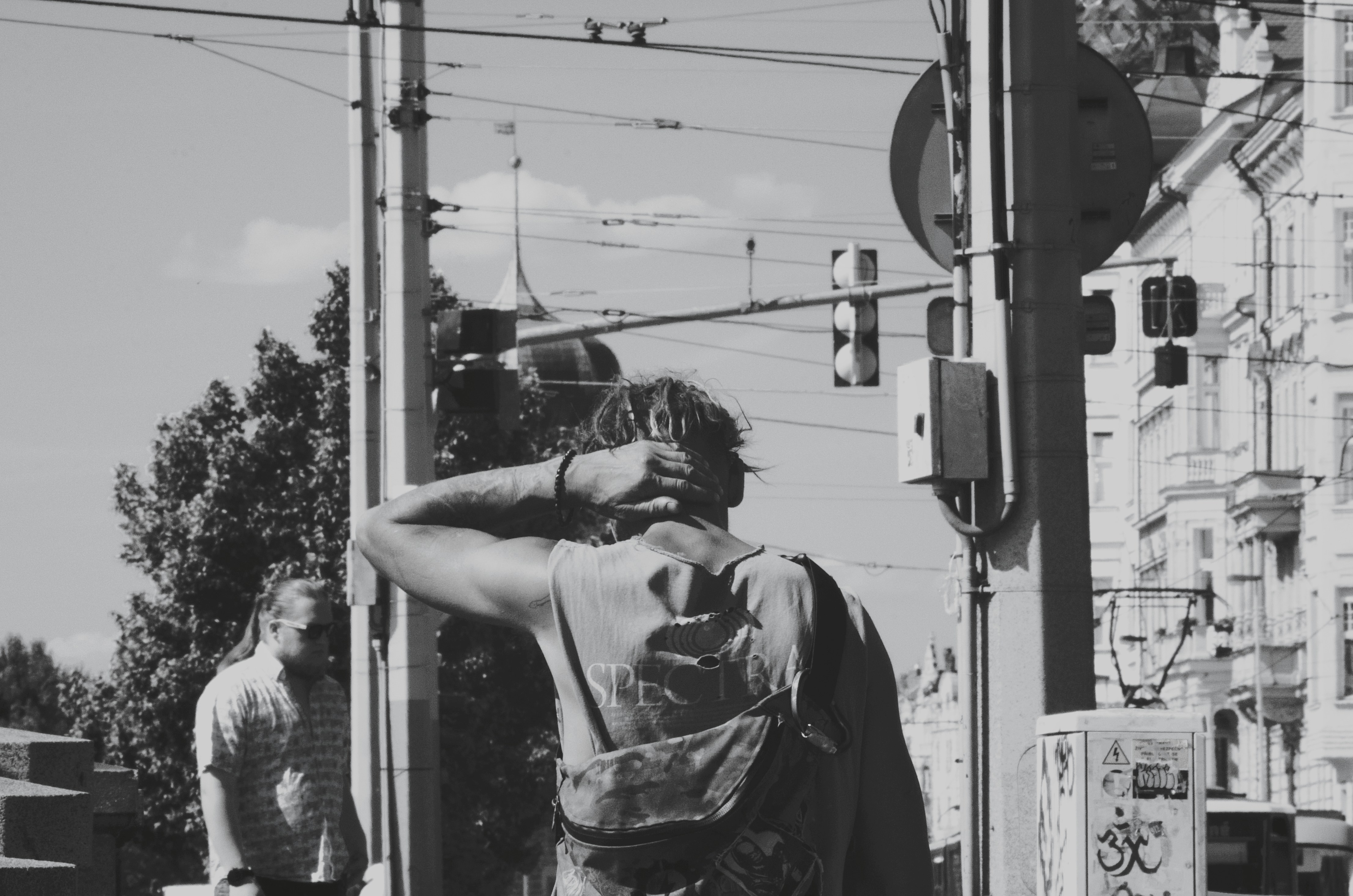 Man on a street corner, looking at traffic.
