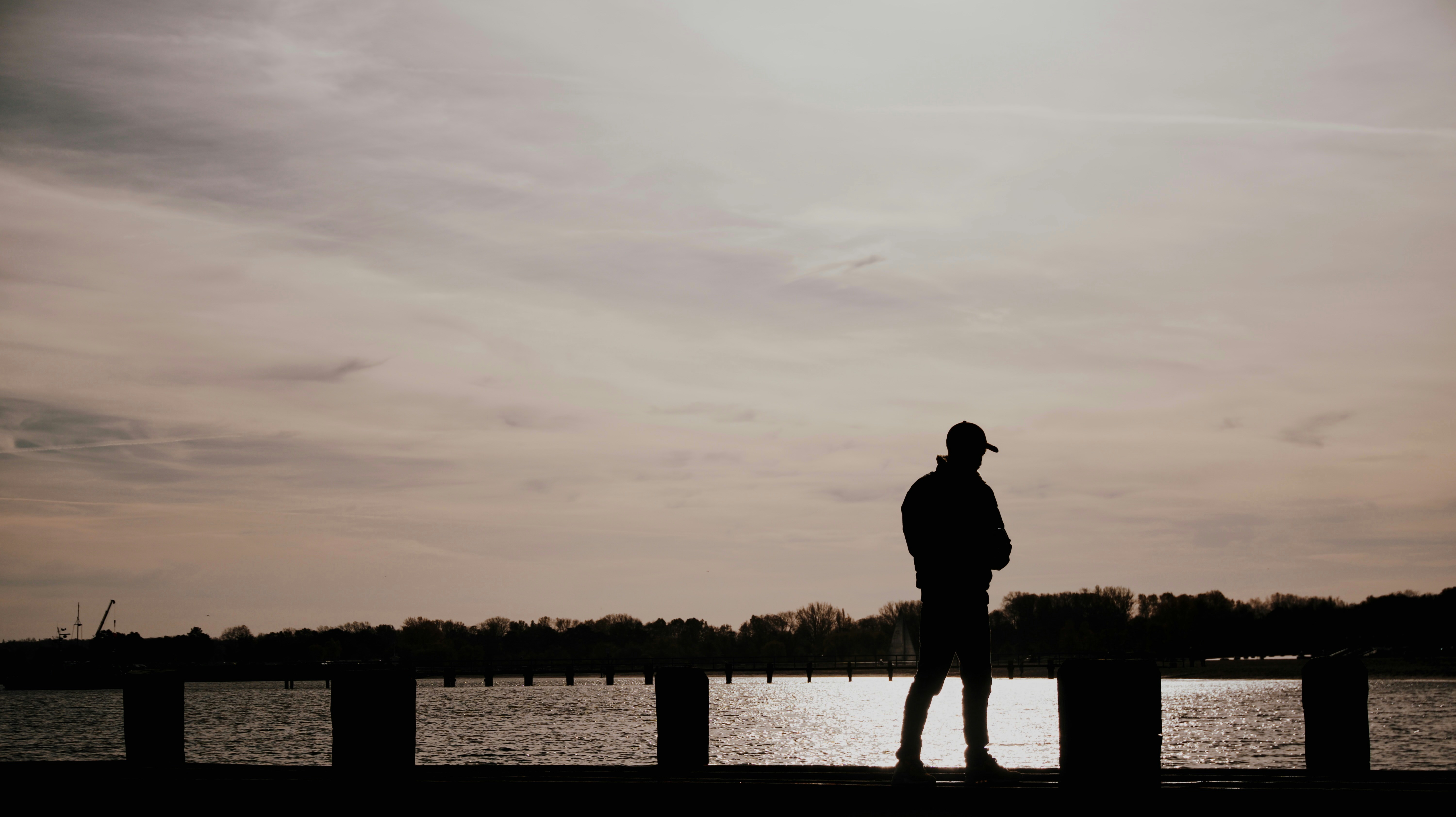 A man stands silhouetted by the water.