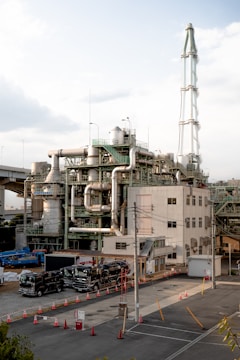 An industrial plant with tall chimney and trucks.