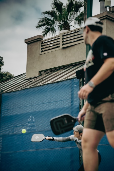 Players on an outdoor pickleball court in sunlight