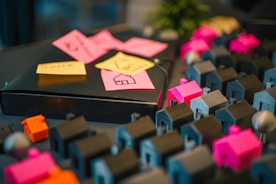 Miniature houses and notes on a dark table.