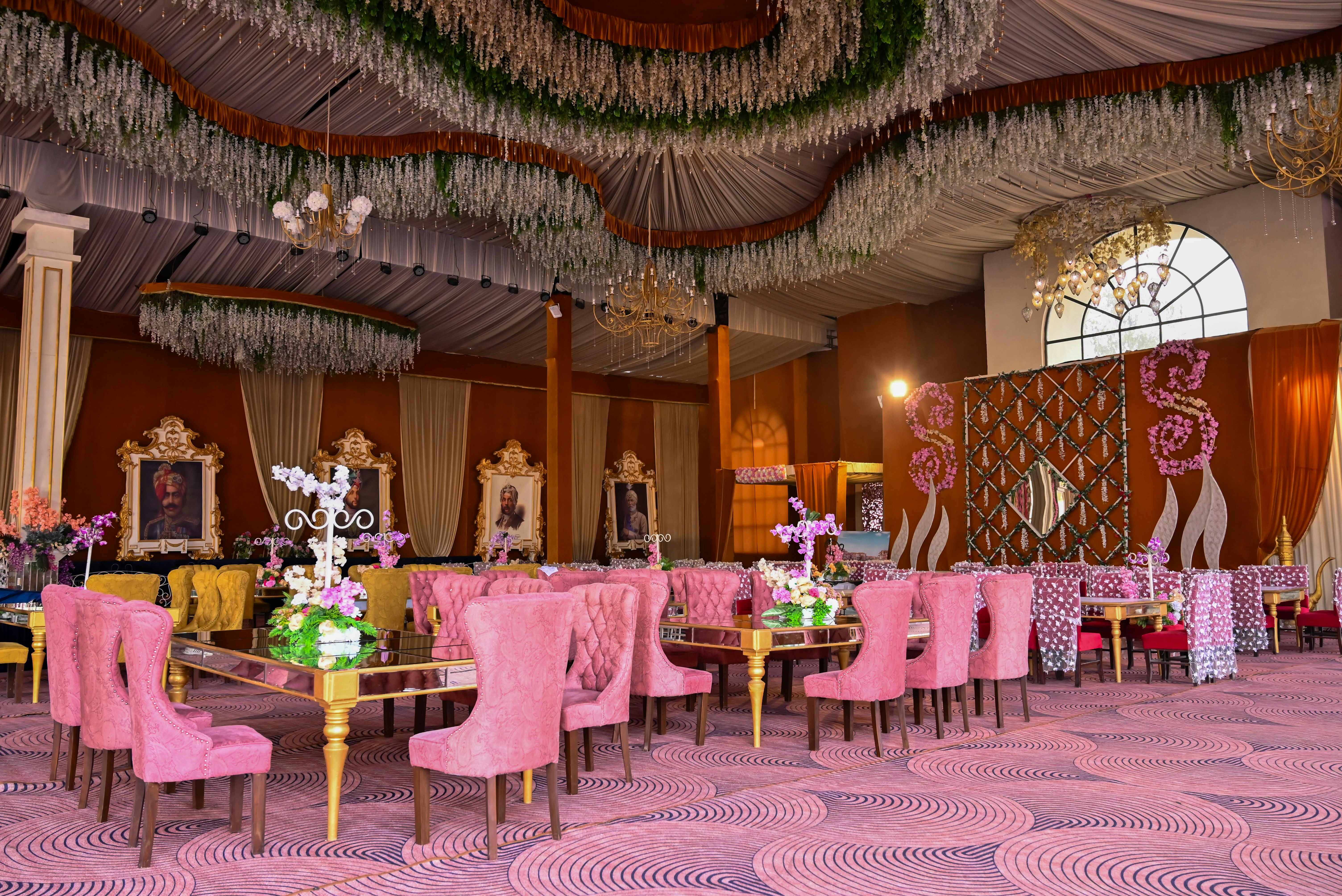 A lavishly decorated event hall with pink chairs.