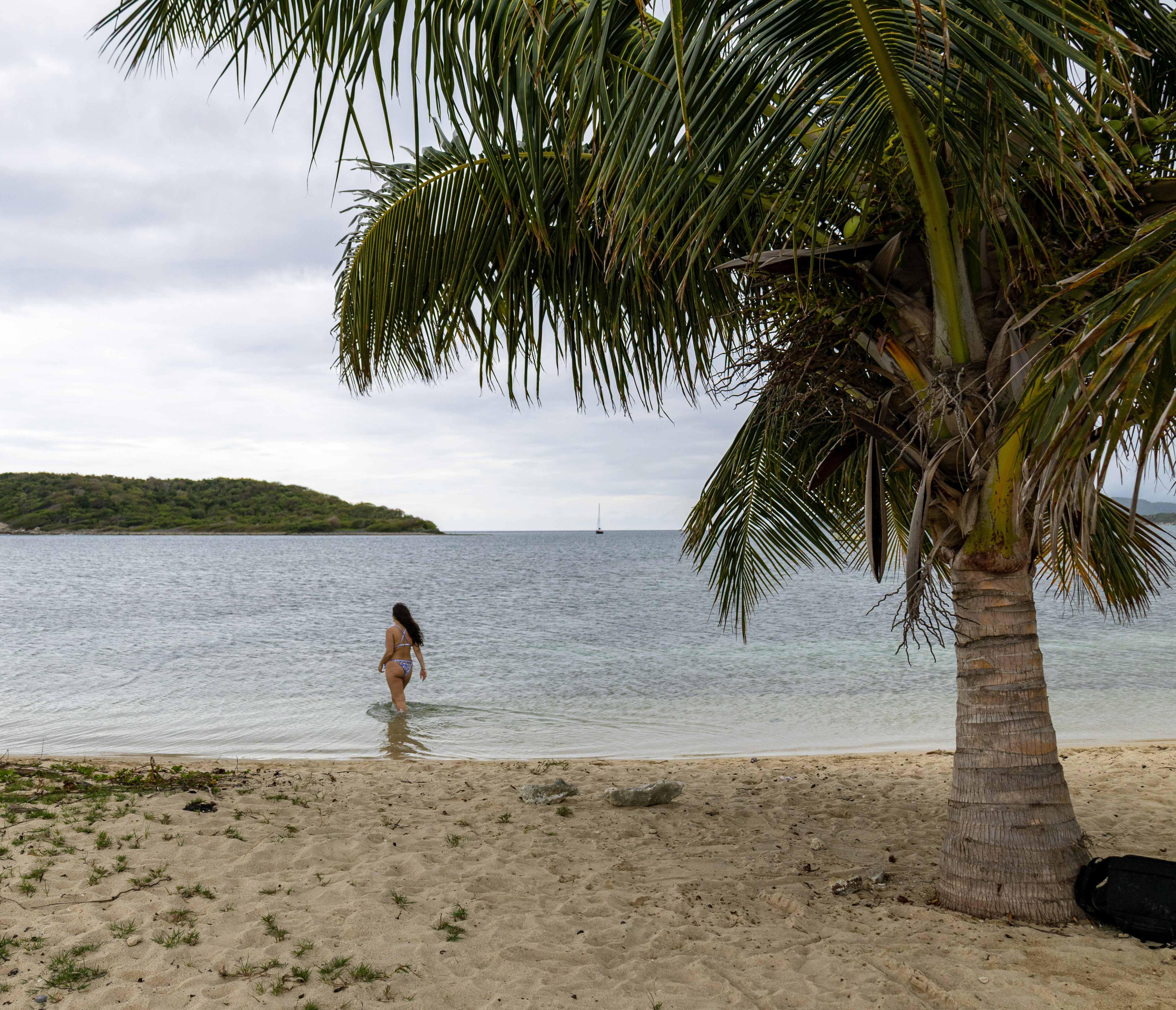 A woman wades into calm ocean water.