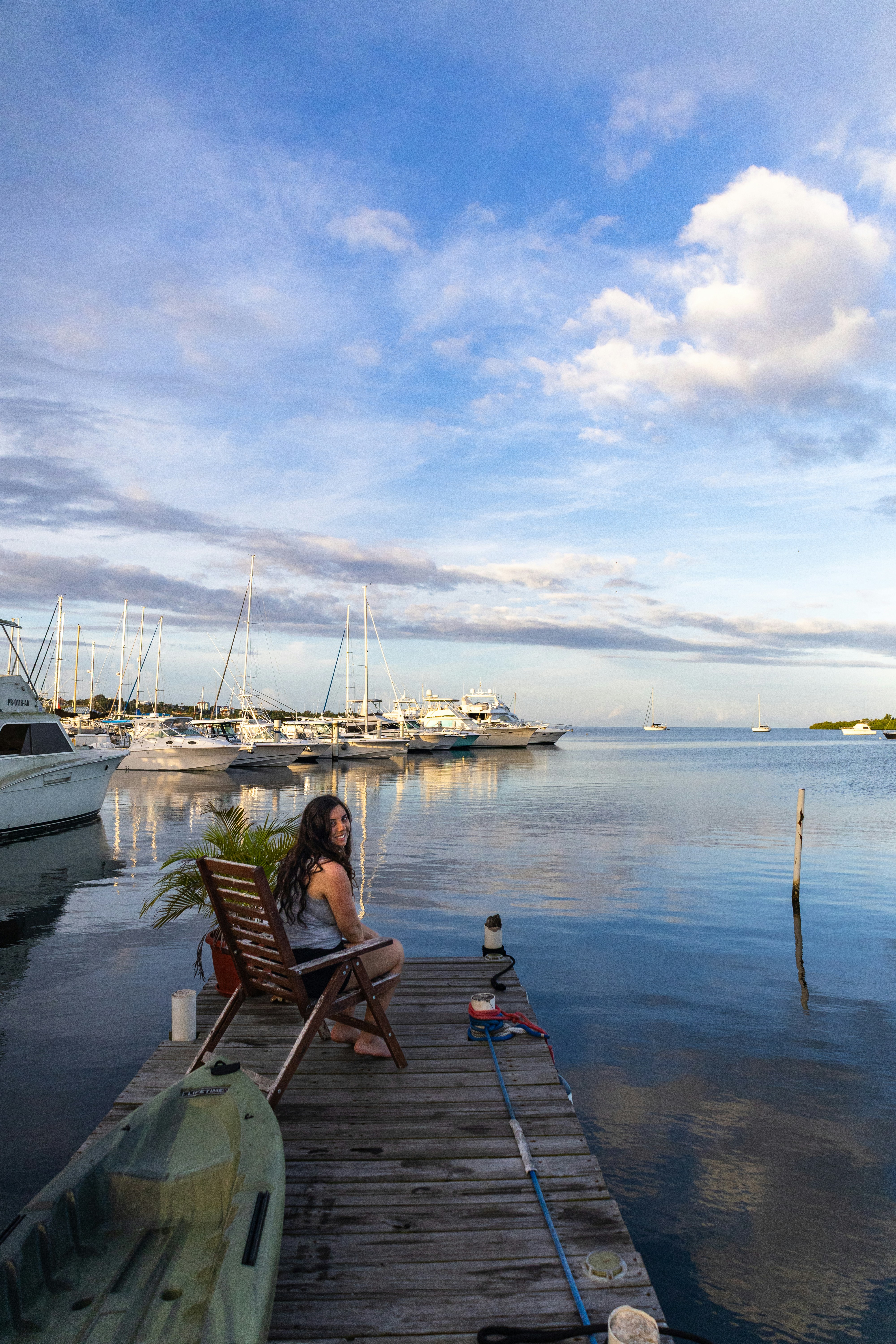 Woman sits on a dock overlooking a marina.