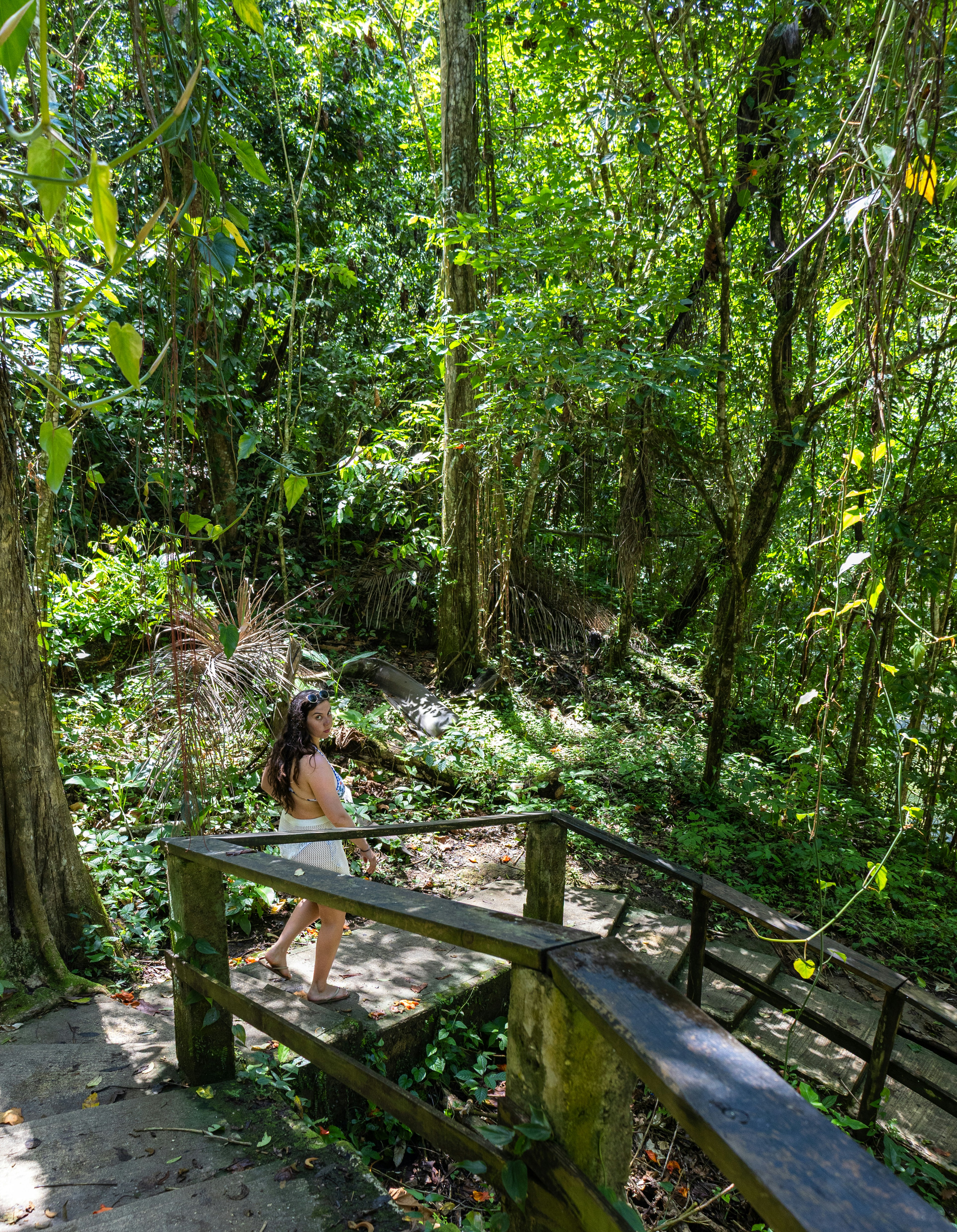 A woman walks down stairs in a lush forest.