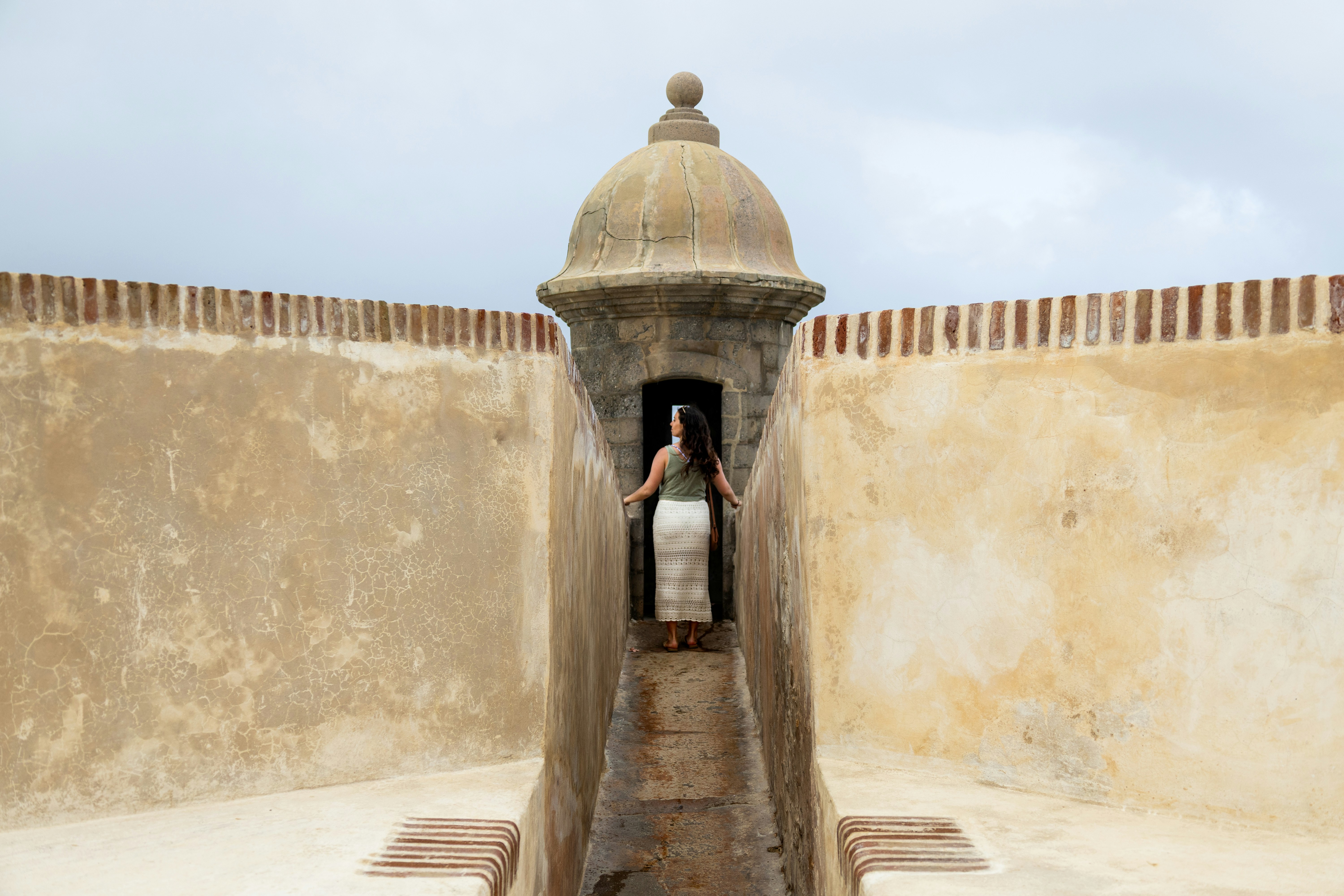 A woman stands in a fort's lookout.