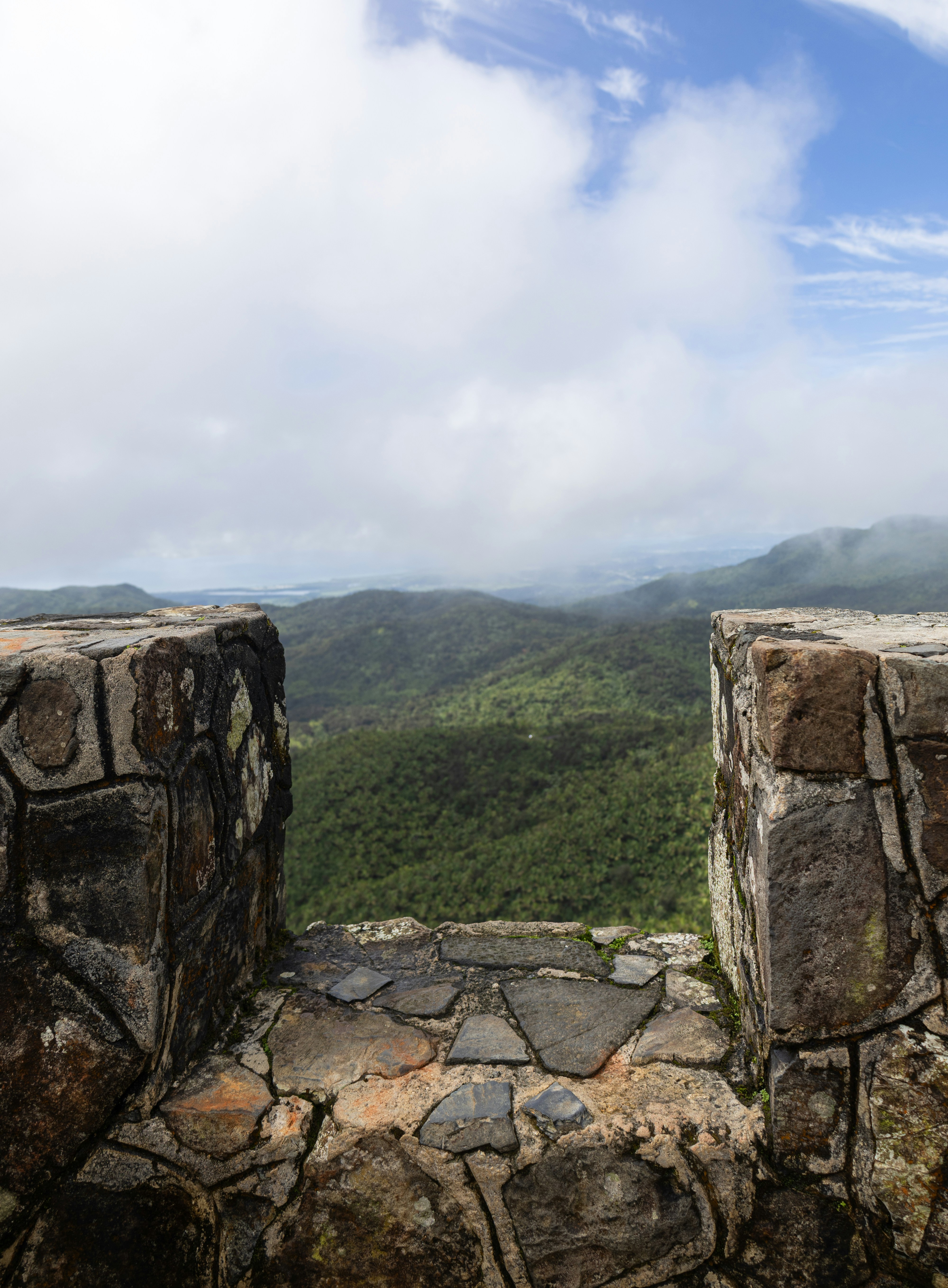 View of lush green hills through stone structure.